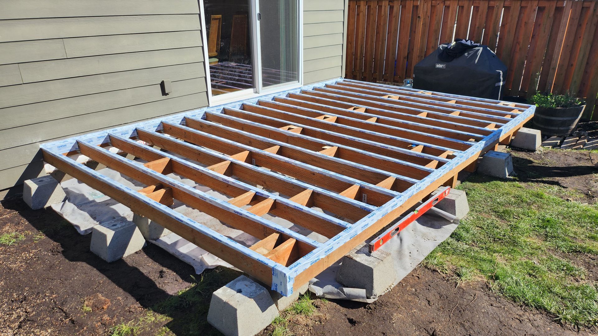 A wooden deck is being built in the backyard of a house.