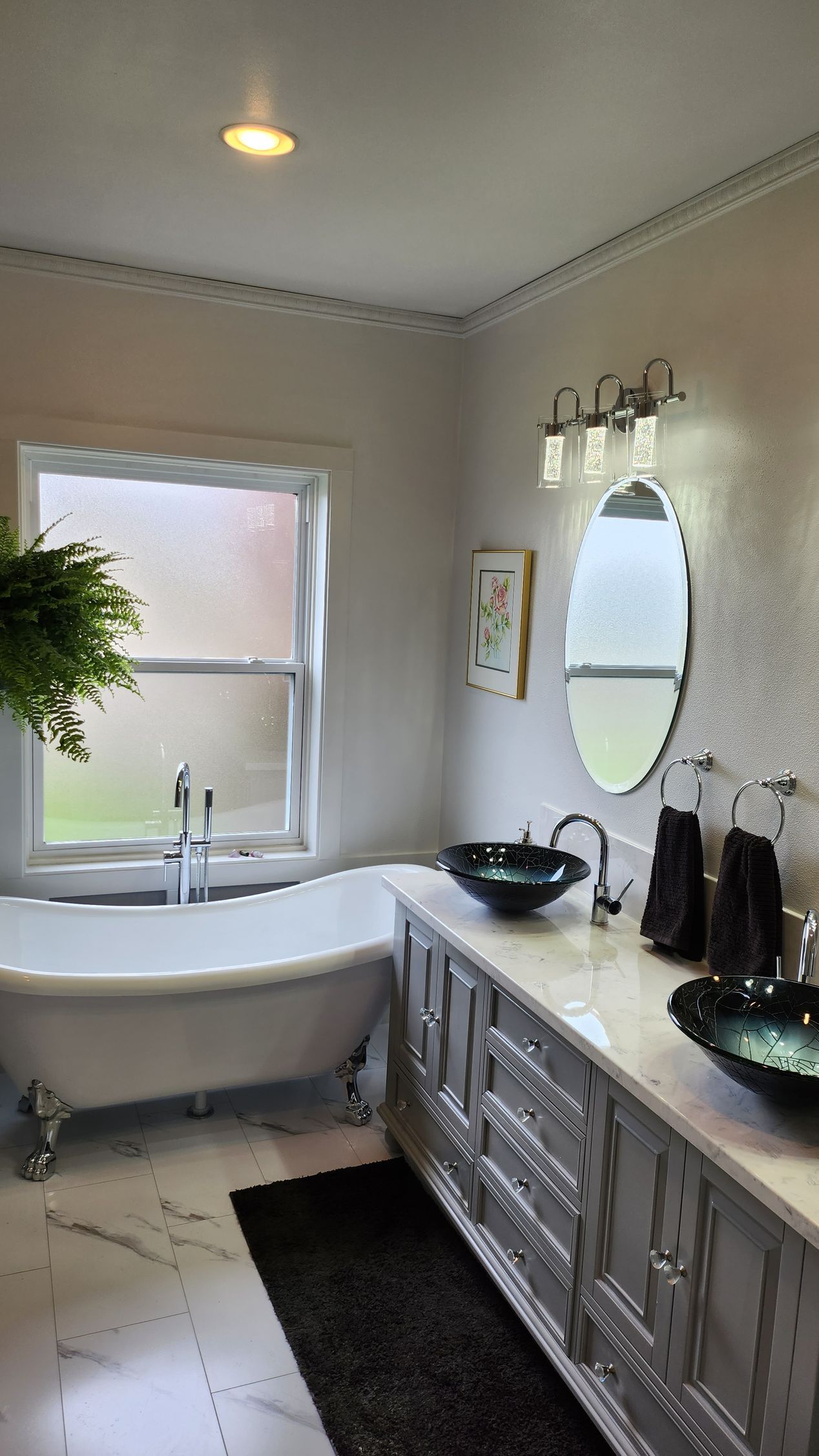 A bathroom with two sinks , a tub and a window.