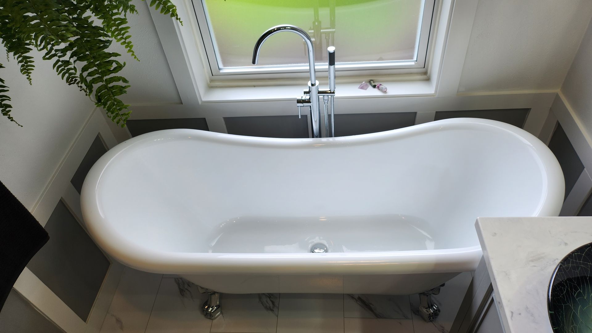 A bathtub in a bathroom next to a window