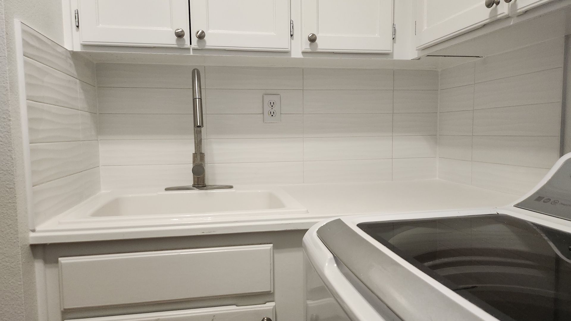 A kitchen with white cabinets , a sink , and a stove.