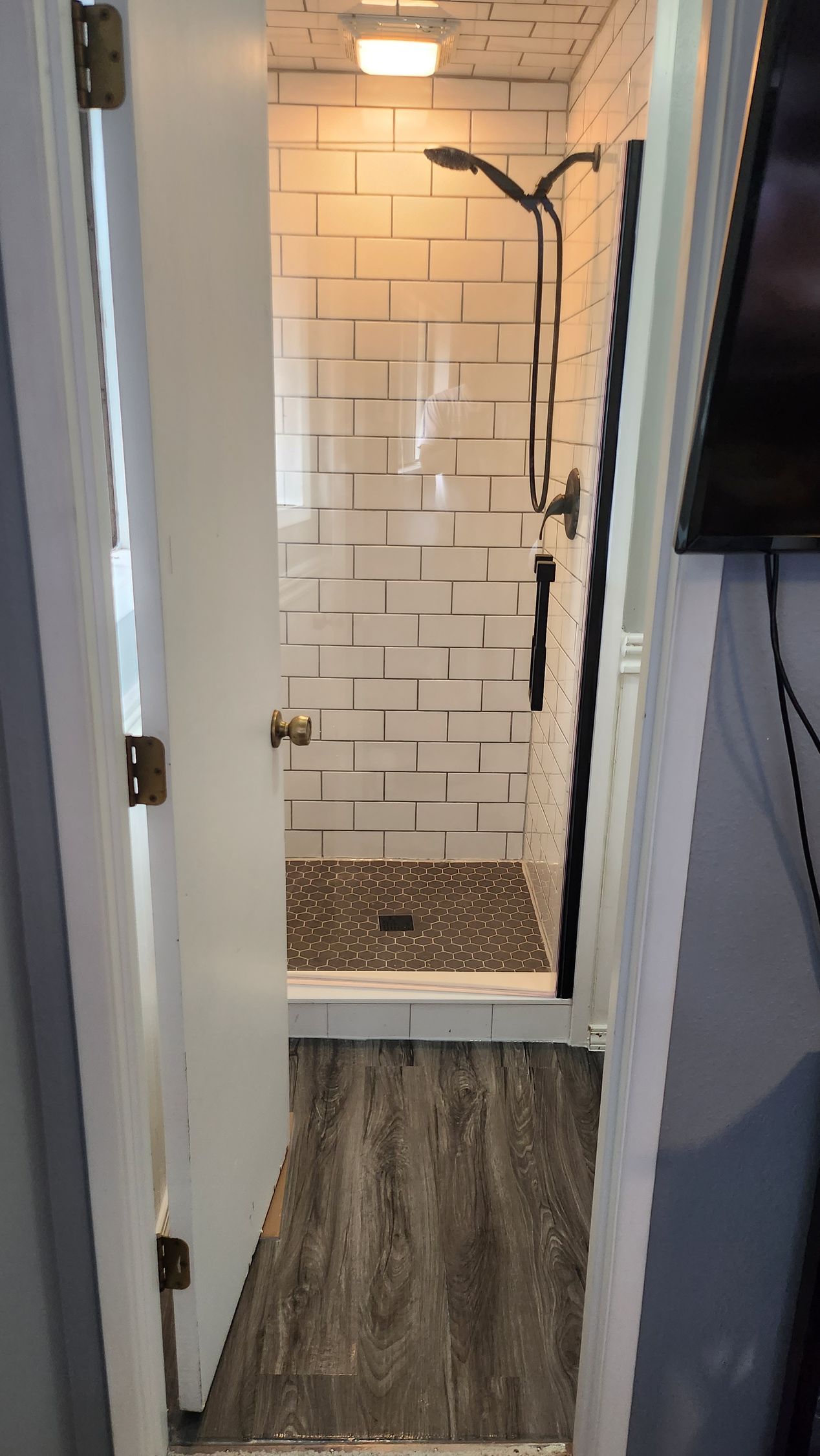 A bathroom with a walk in shower and a door open.