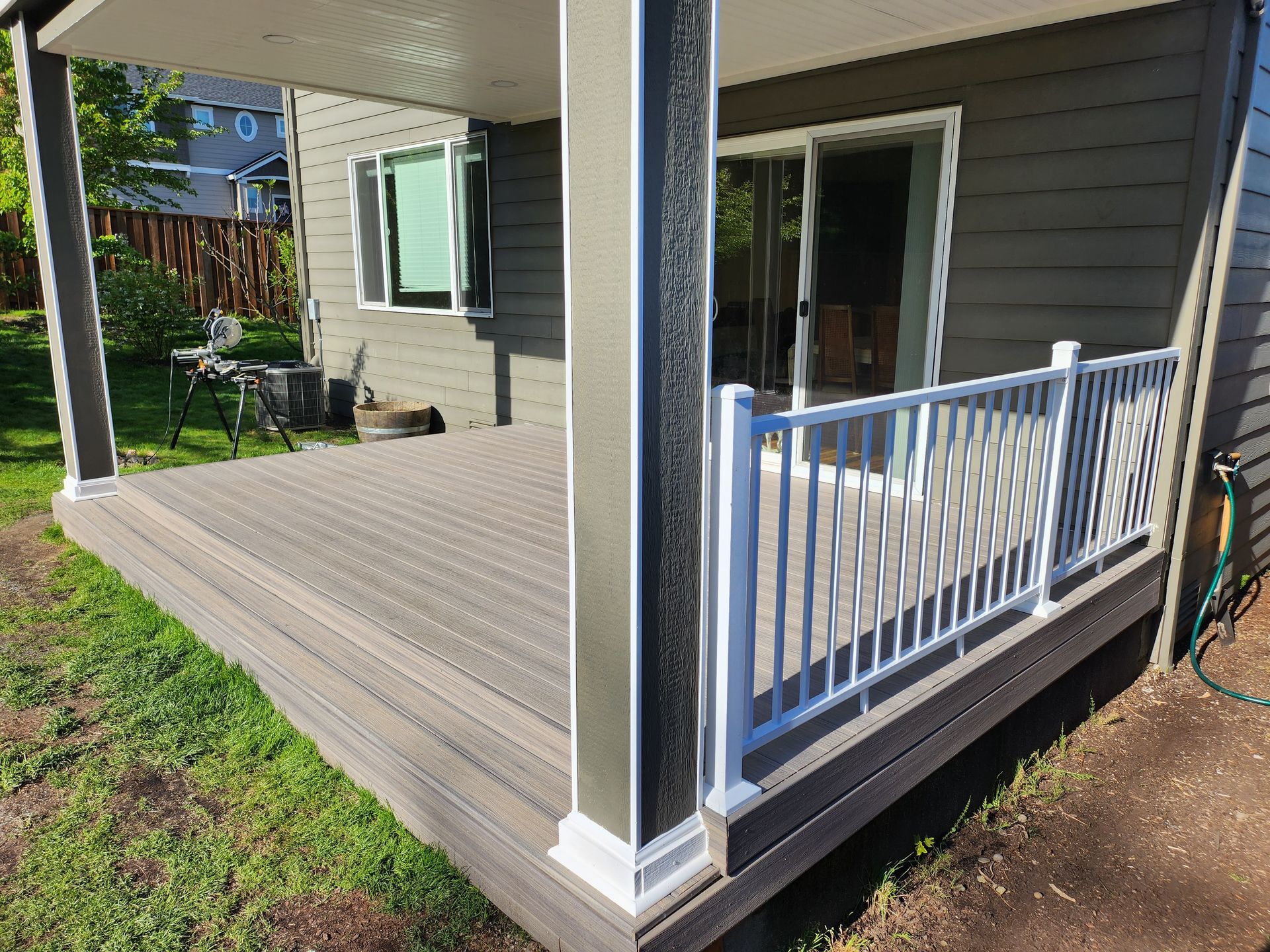 There is a deck with a white railing and a sliding glass door.