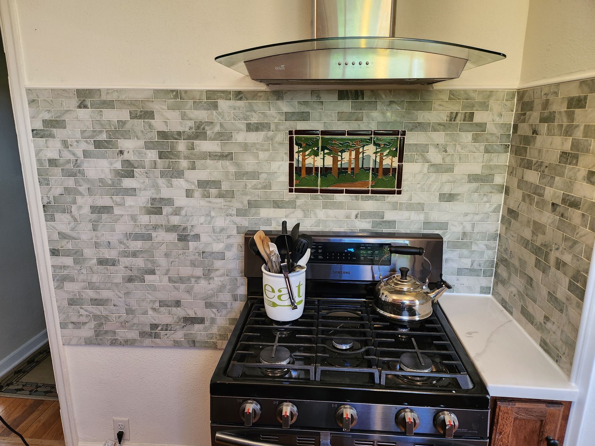 A stove with a hood and a pot on it in a kitchen.