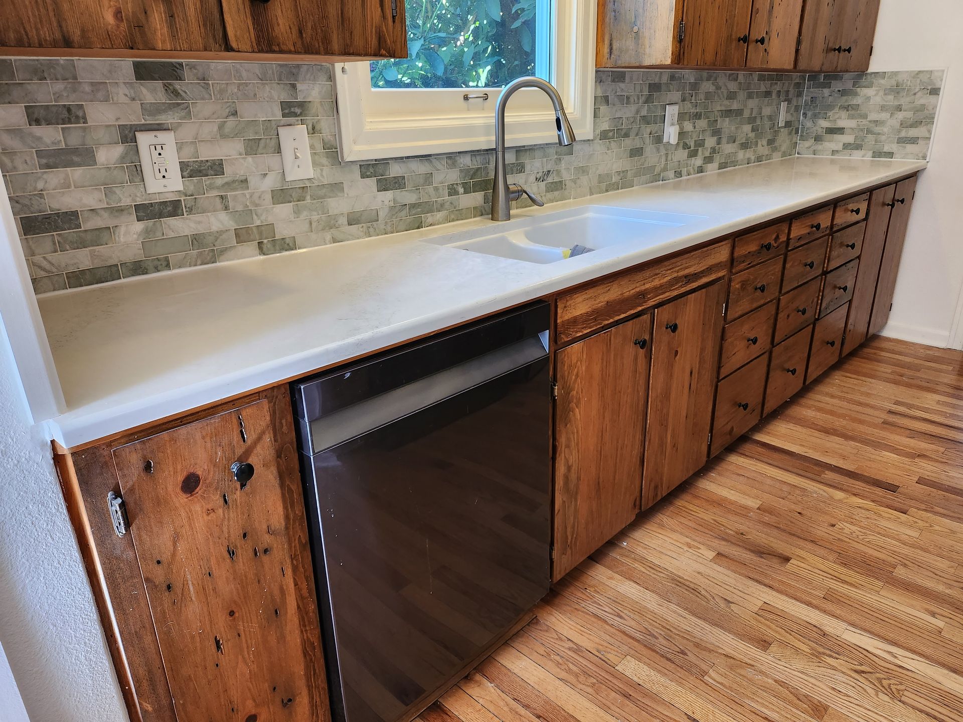 A kitchen with wooden cabinets and a stainless steel dishwasher
