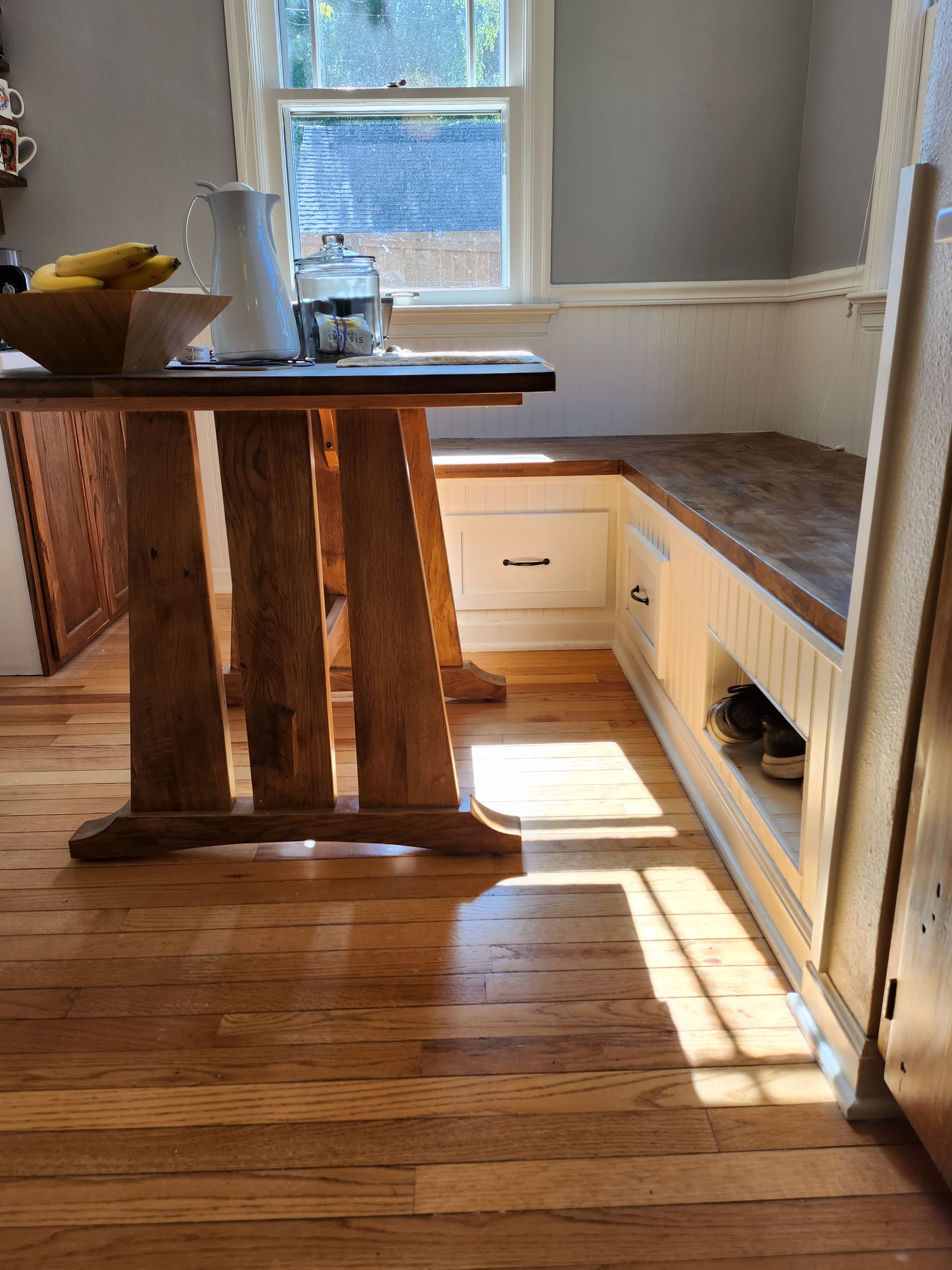 A wooden table in a kitchen next to a window.