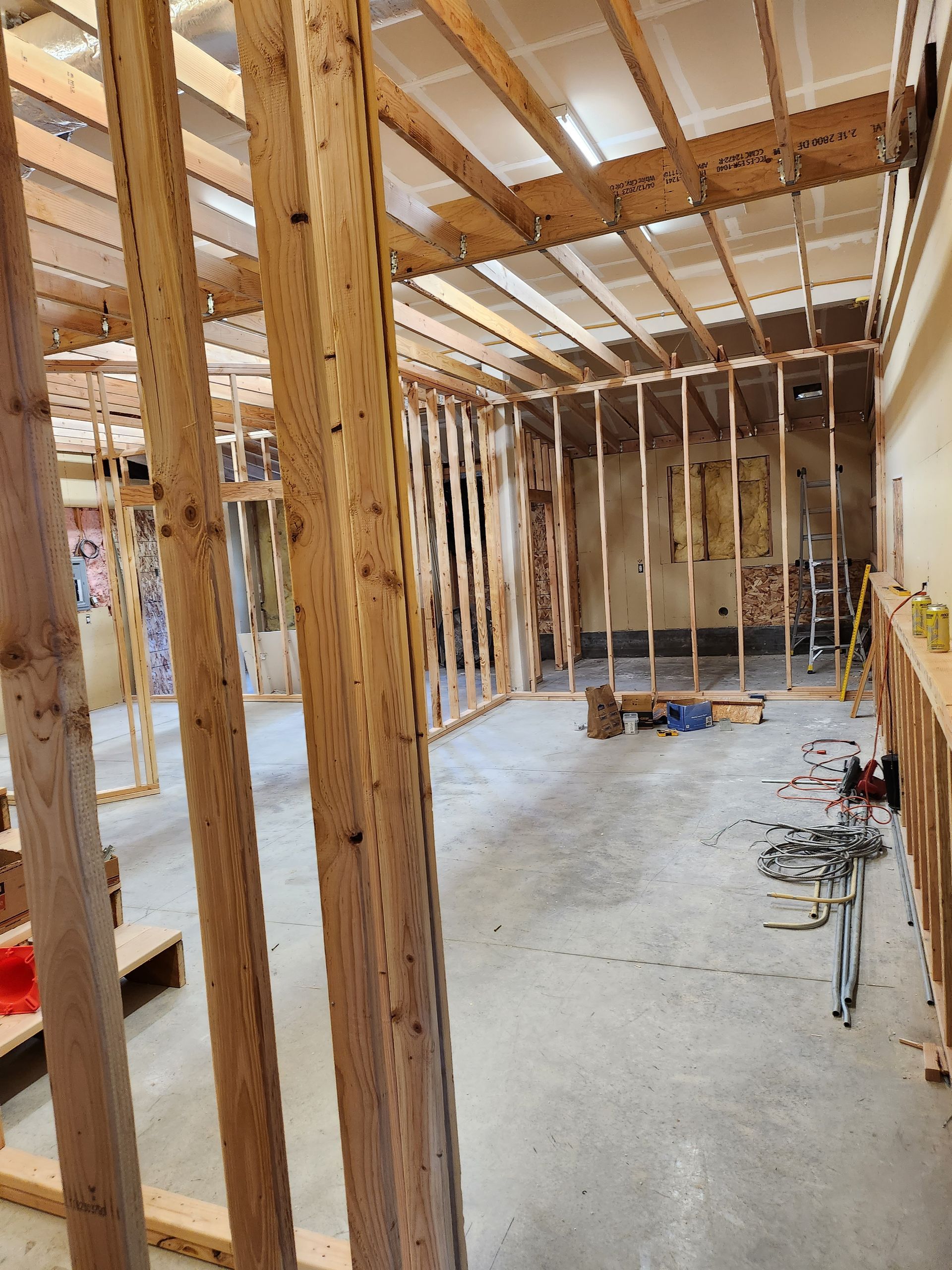 A room under construction with wooden beams and a concrete floor.