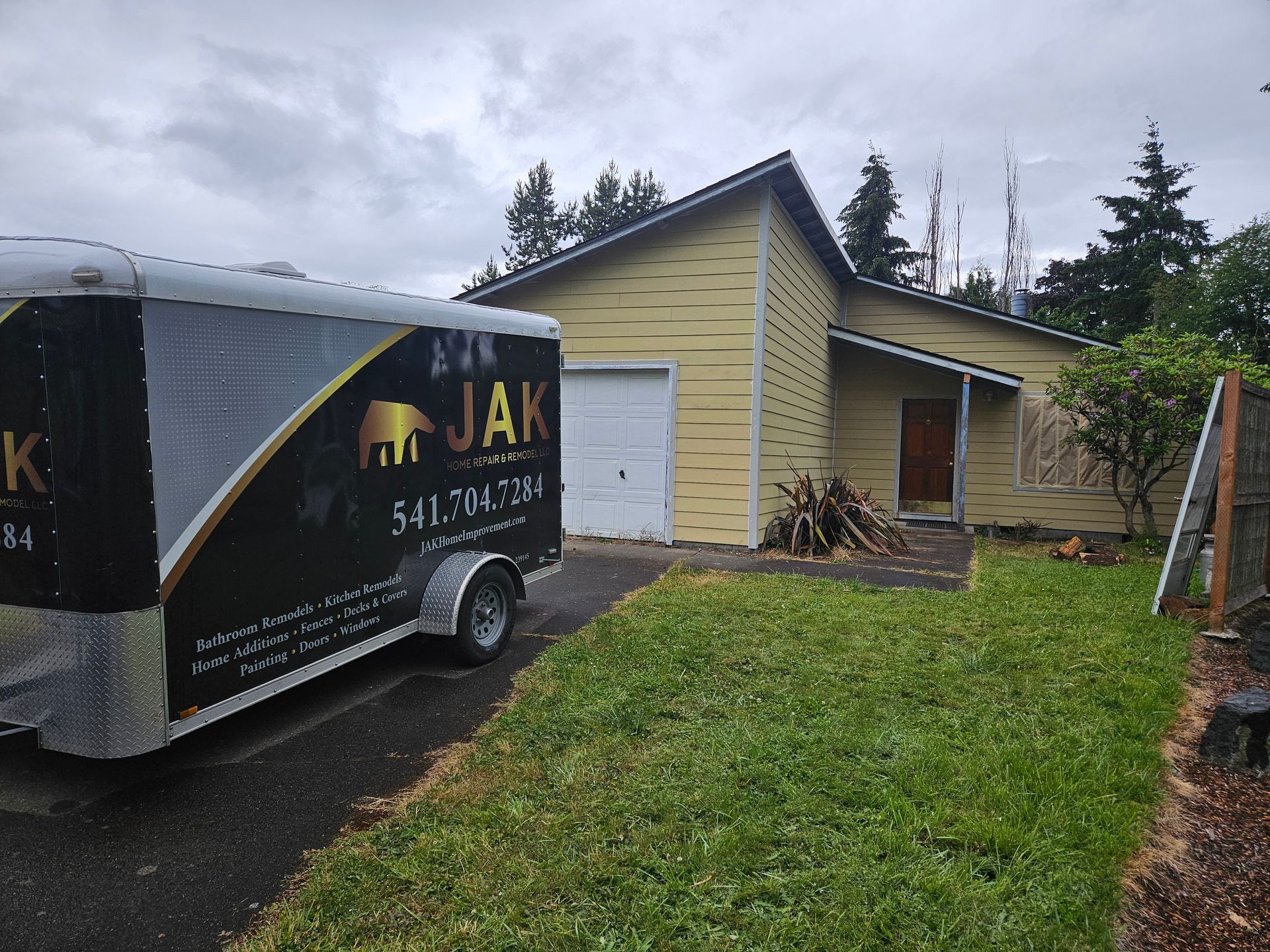 A truck with the word jak on it is parked in front of a house.
