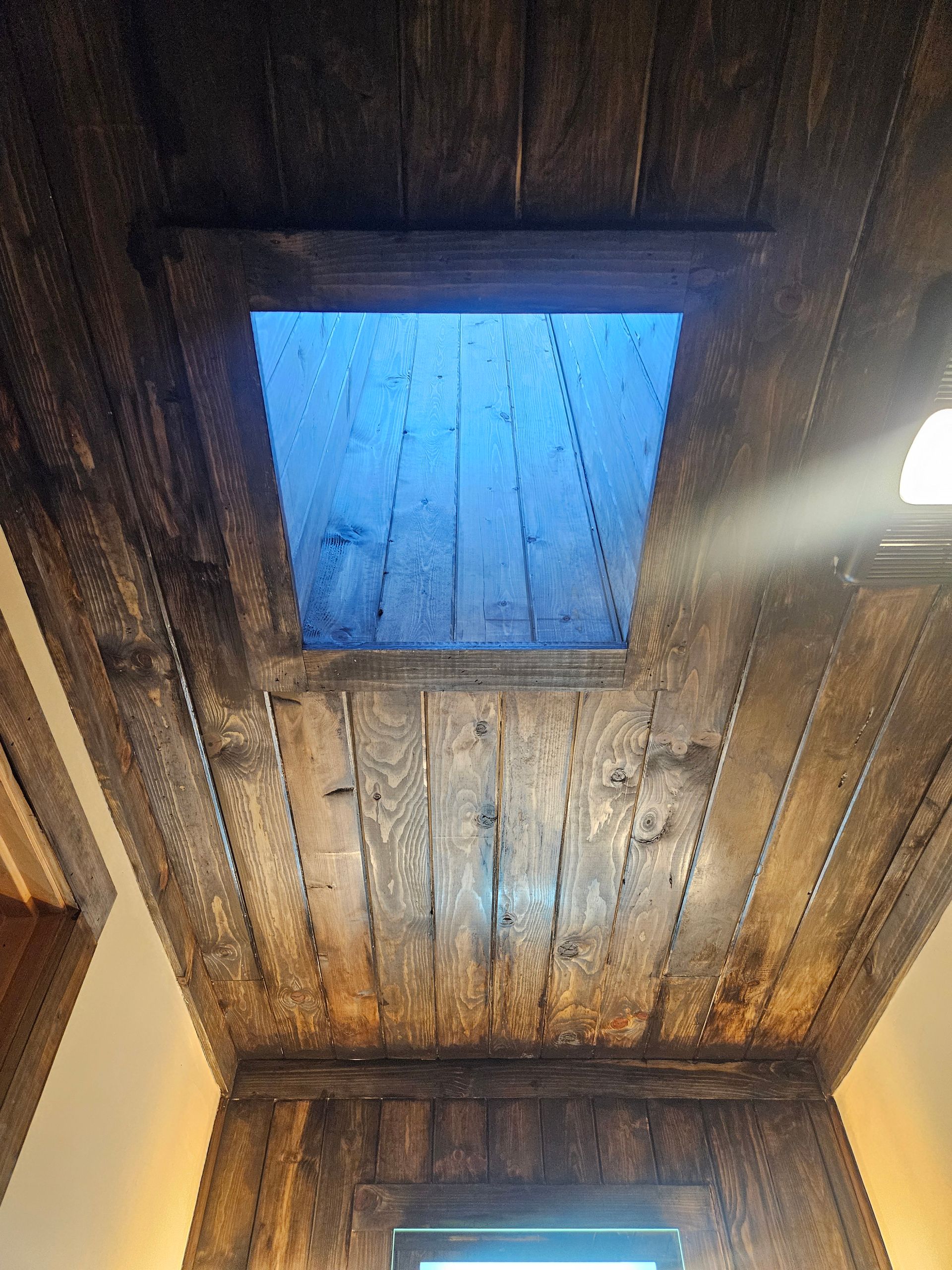 A bathroom with a wooden ceiling and a skylight.