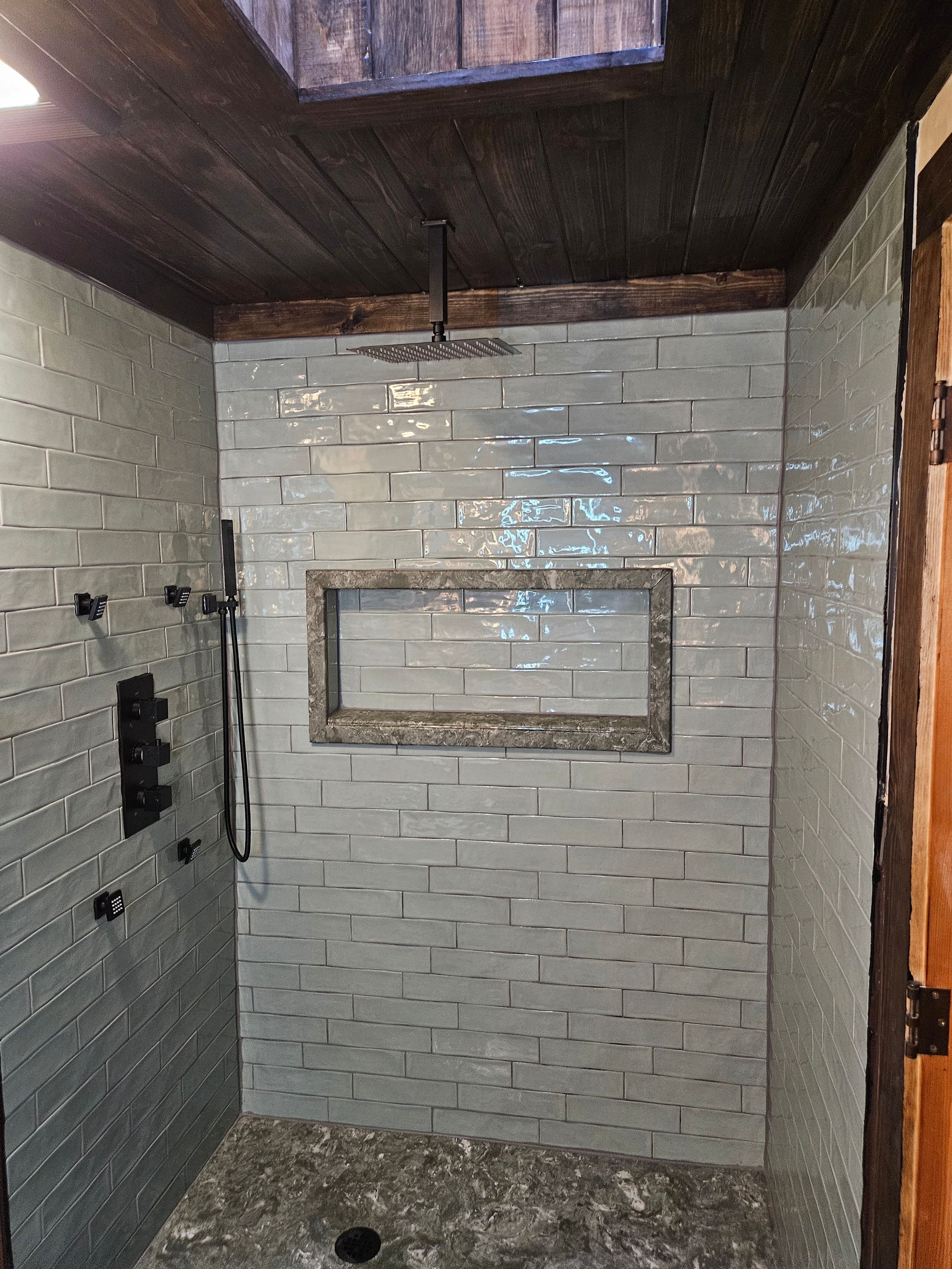 A bathroom with a walk in shower and a skylight.