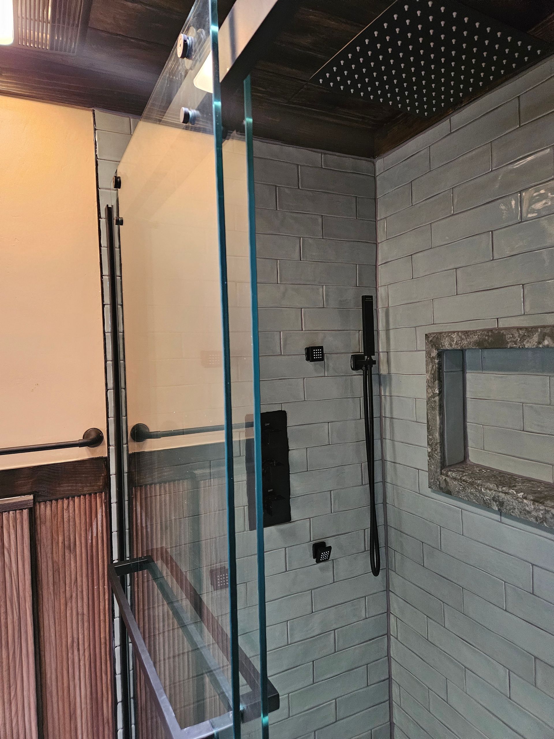 There is a shower with a glass door and a shower head.