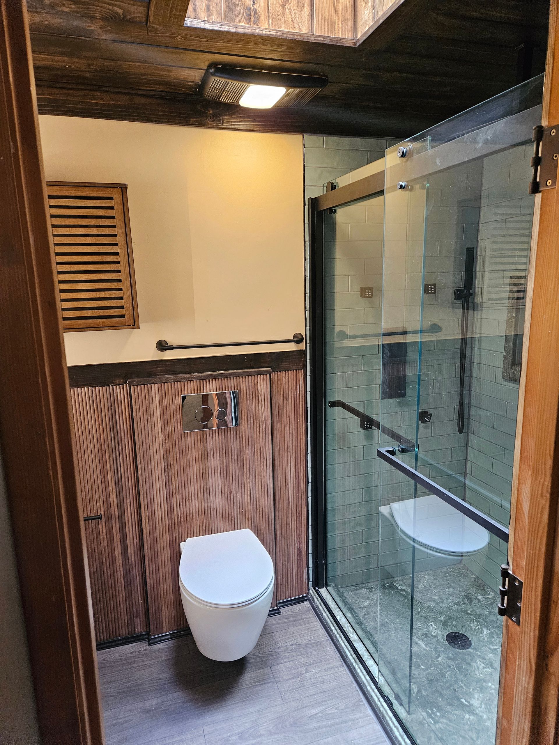 A bathroom with a toilet and a walk in shower.