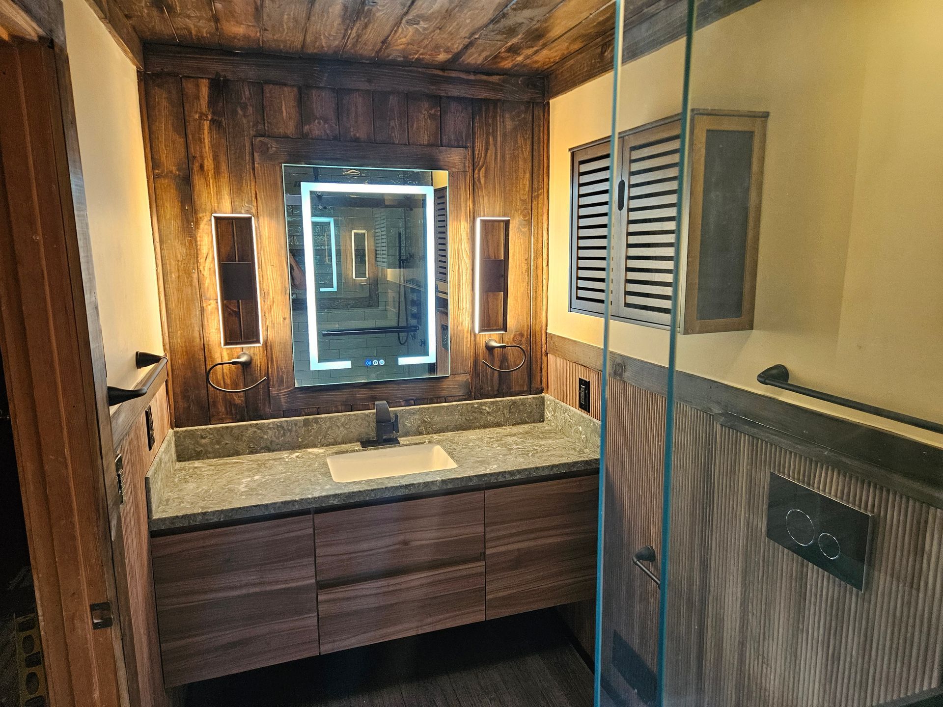 A bathroom with a sink , mirror , and wooden cabinets.