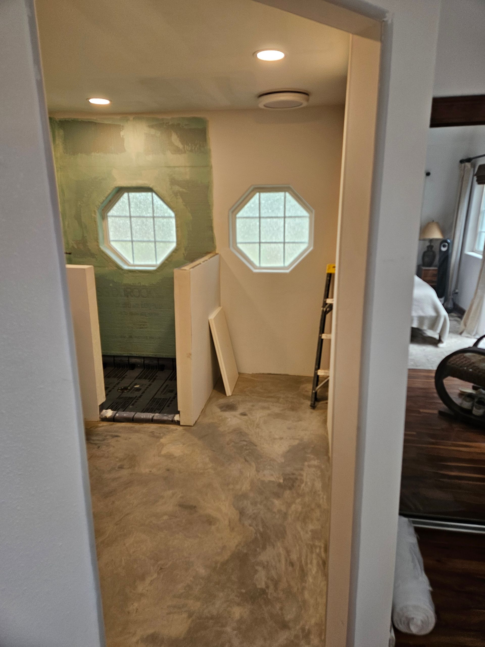A bathroom with a walk in shower and two windows.