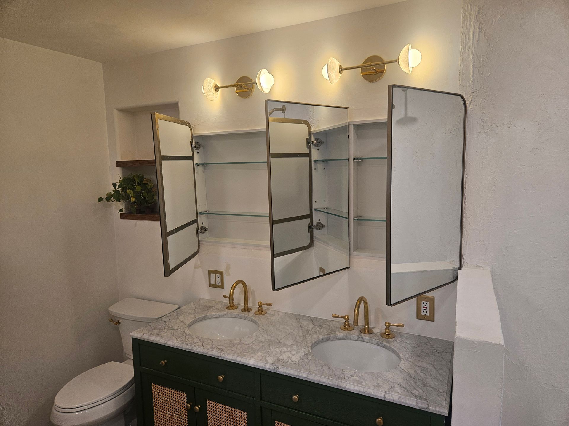 A bathroom with two sinks , a toilet , and a medicine cabinet.