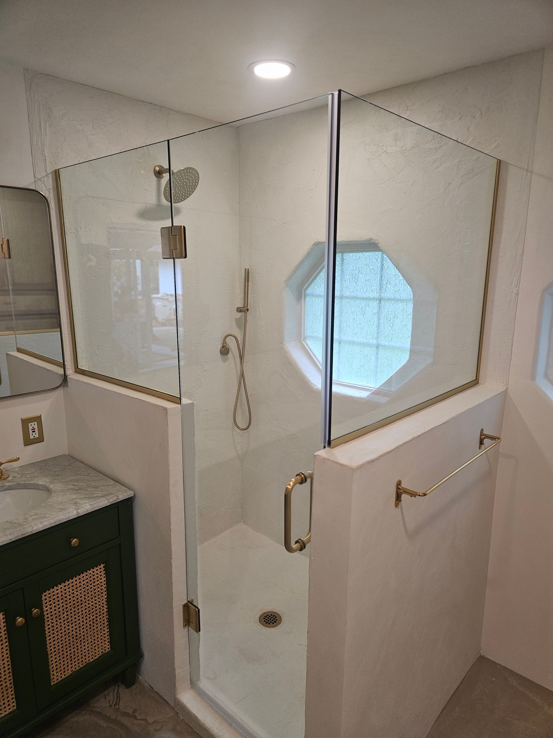 A bathroom with a walk in shower and a sink