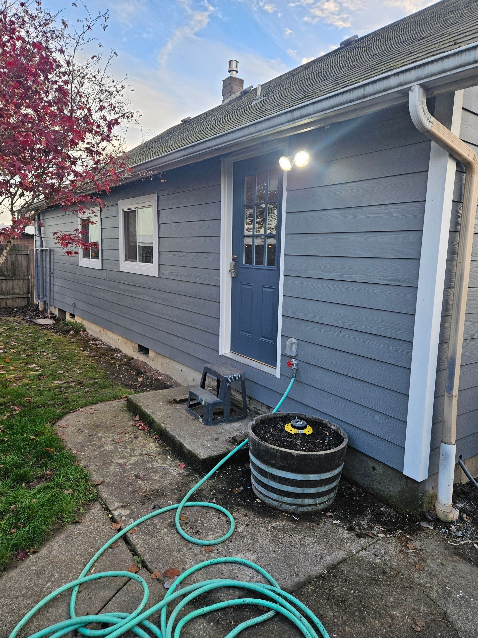 A hose is sitting on the sidewalk in front of a house.