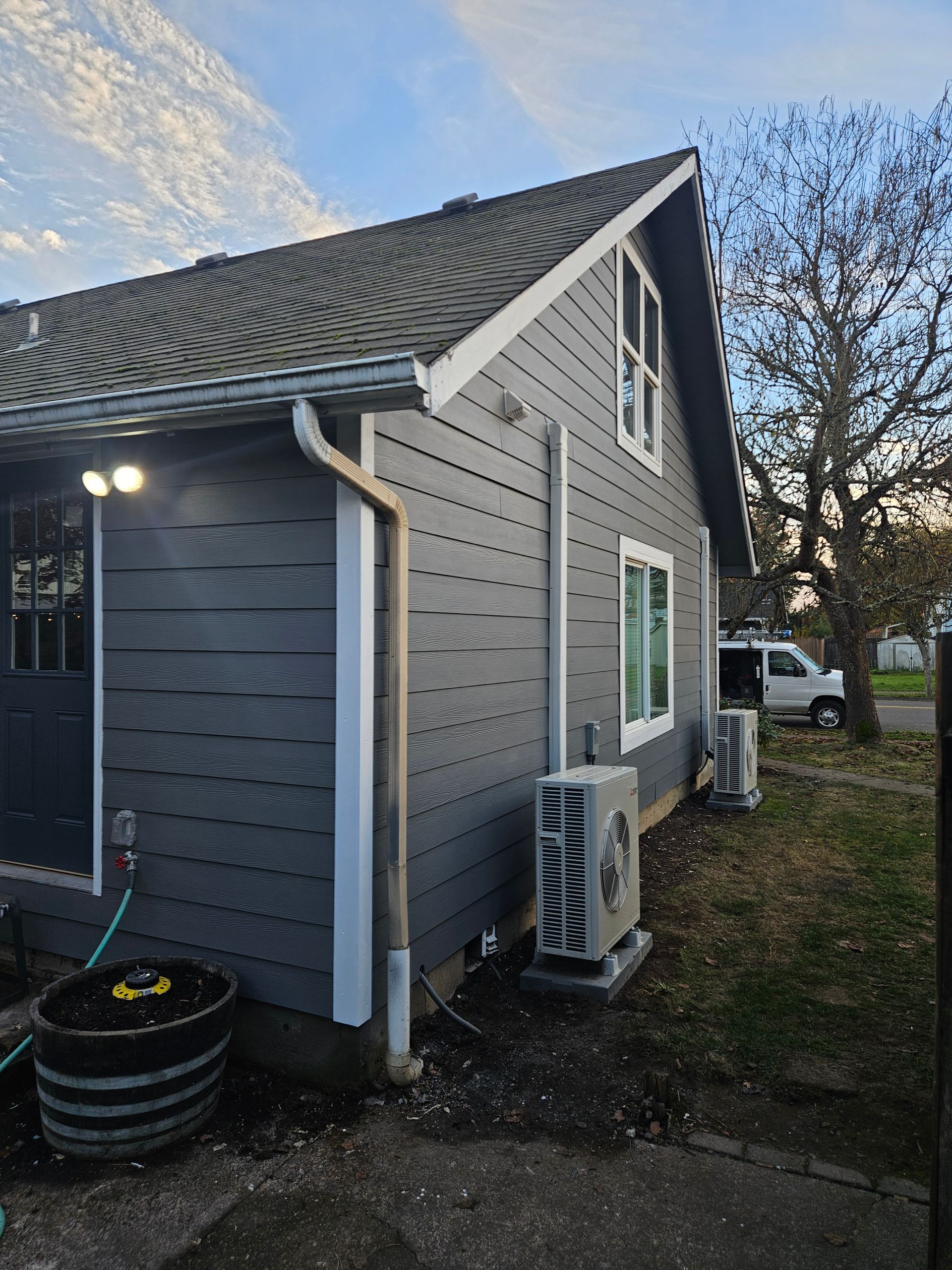 A gray house with a black door and a white trim