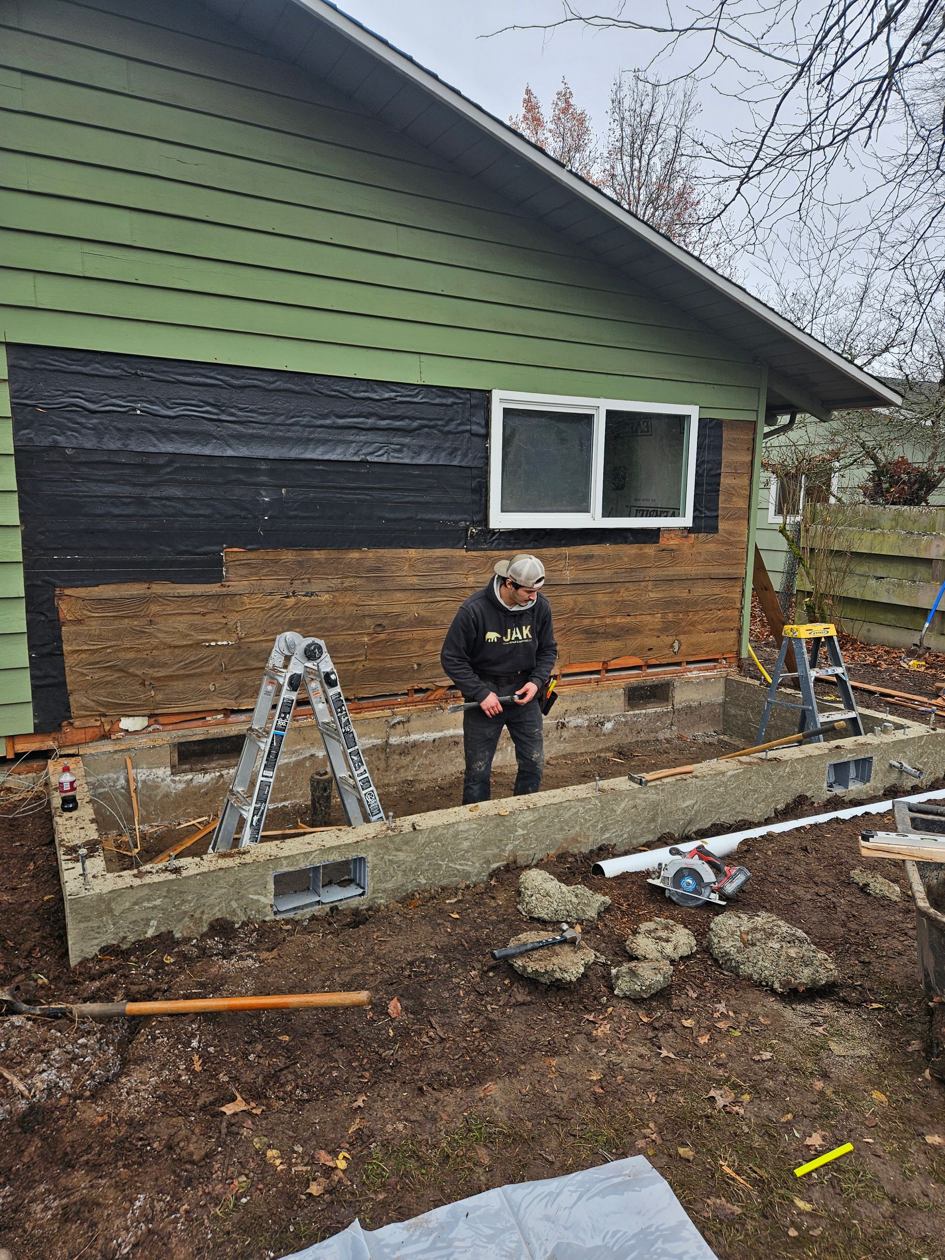 A man is standing in front of a green house.