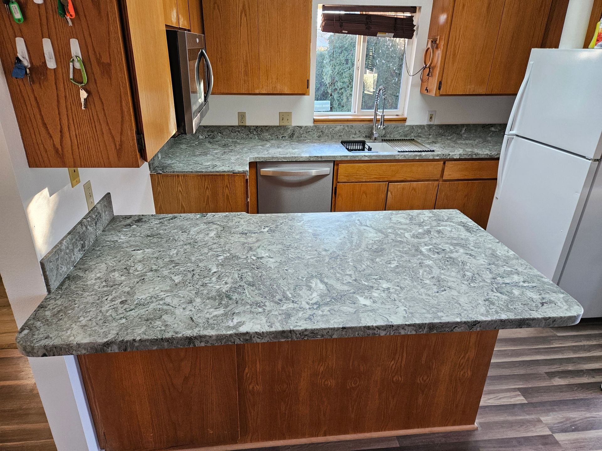 A kitchen with granite counter tops and wooden cabinets.