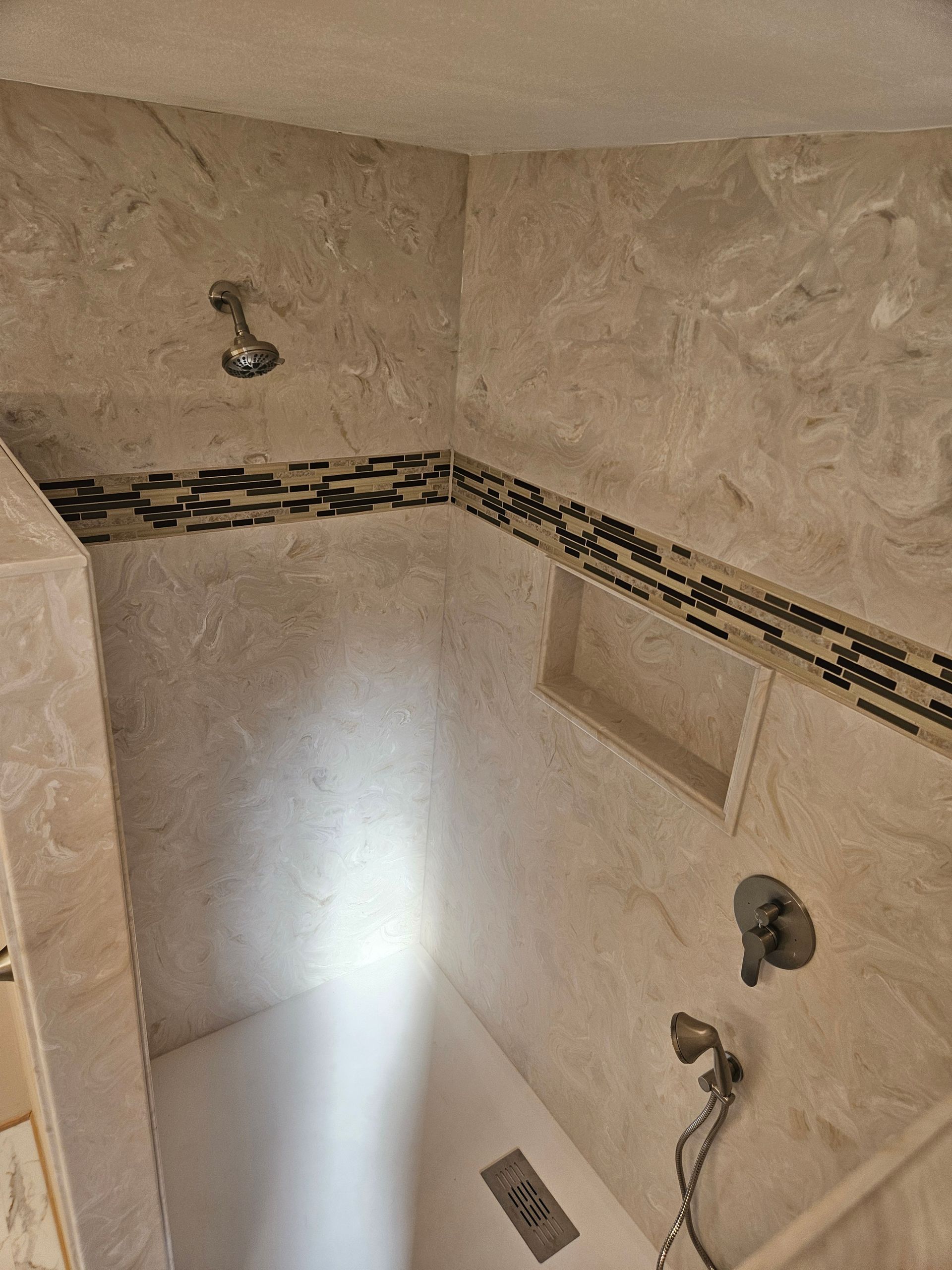 A shower with a shower head and a shelf underneath it