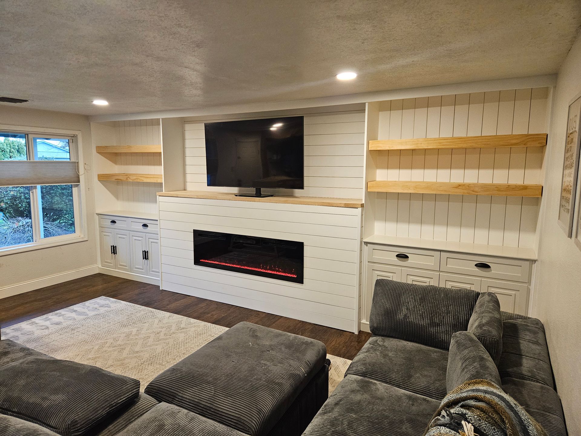 A living room with a fireplace , couch , television and shelves.