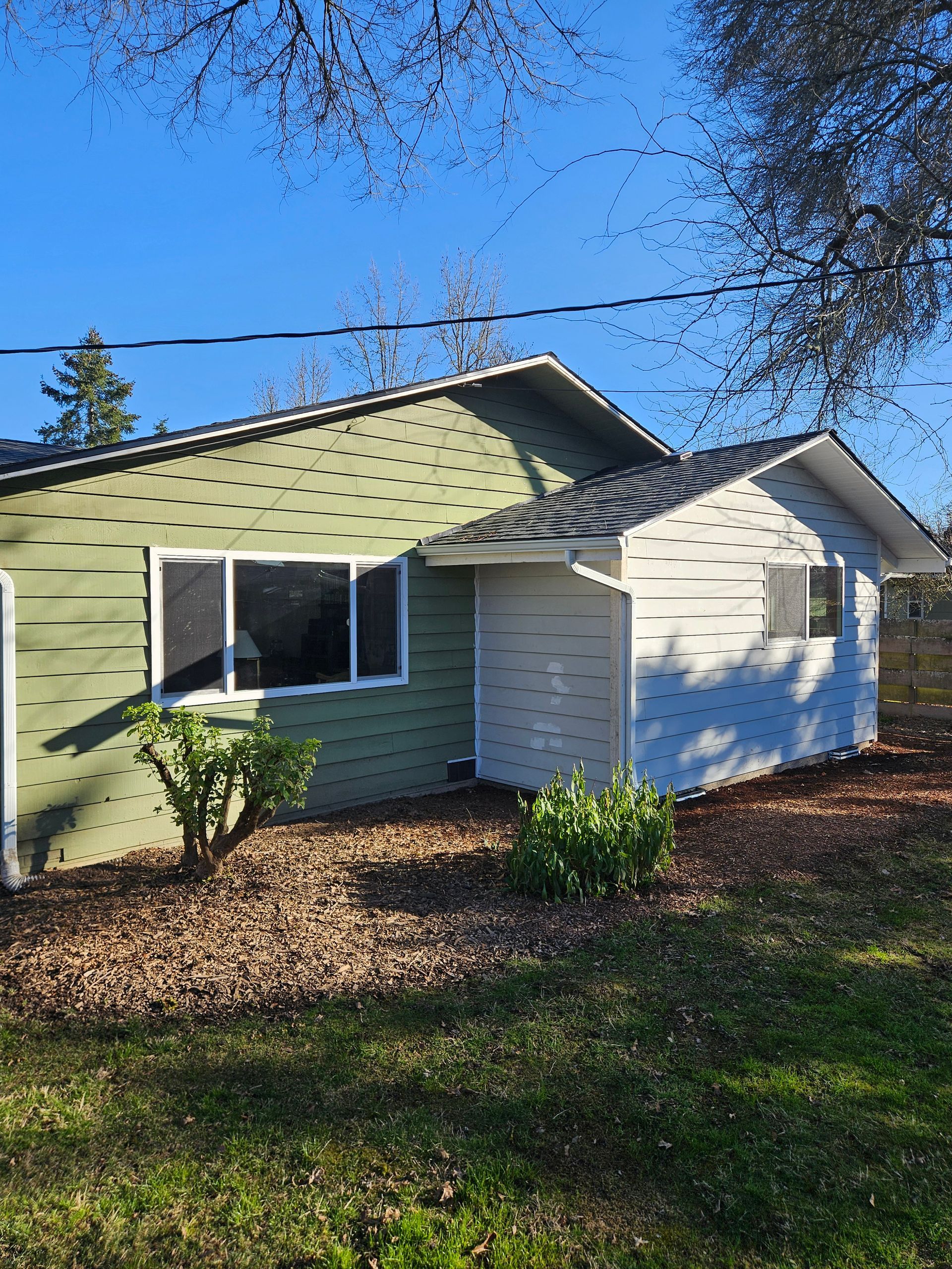 A small house with green siding and white trim addition