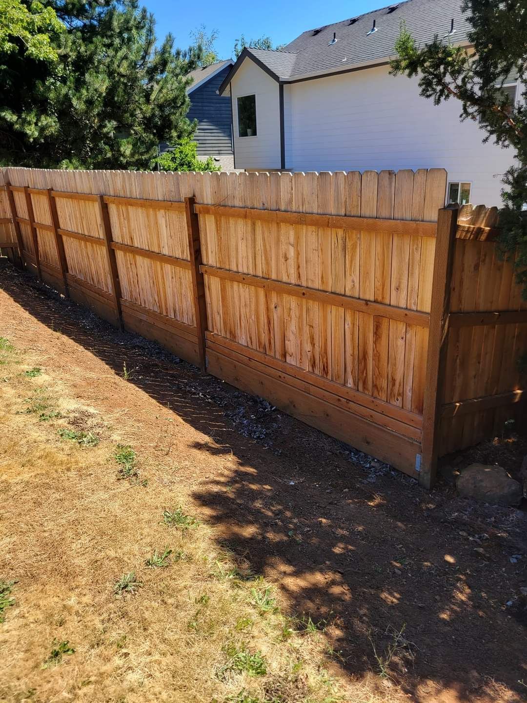 A wooden fence is in the backyard of a house.