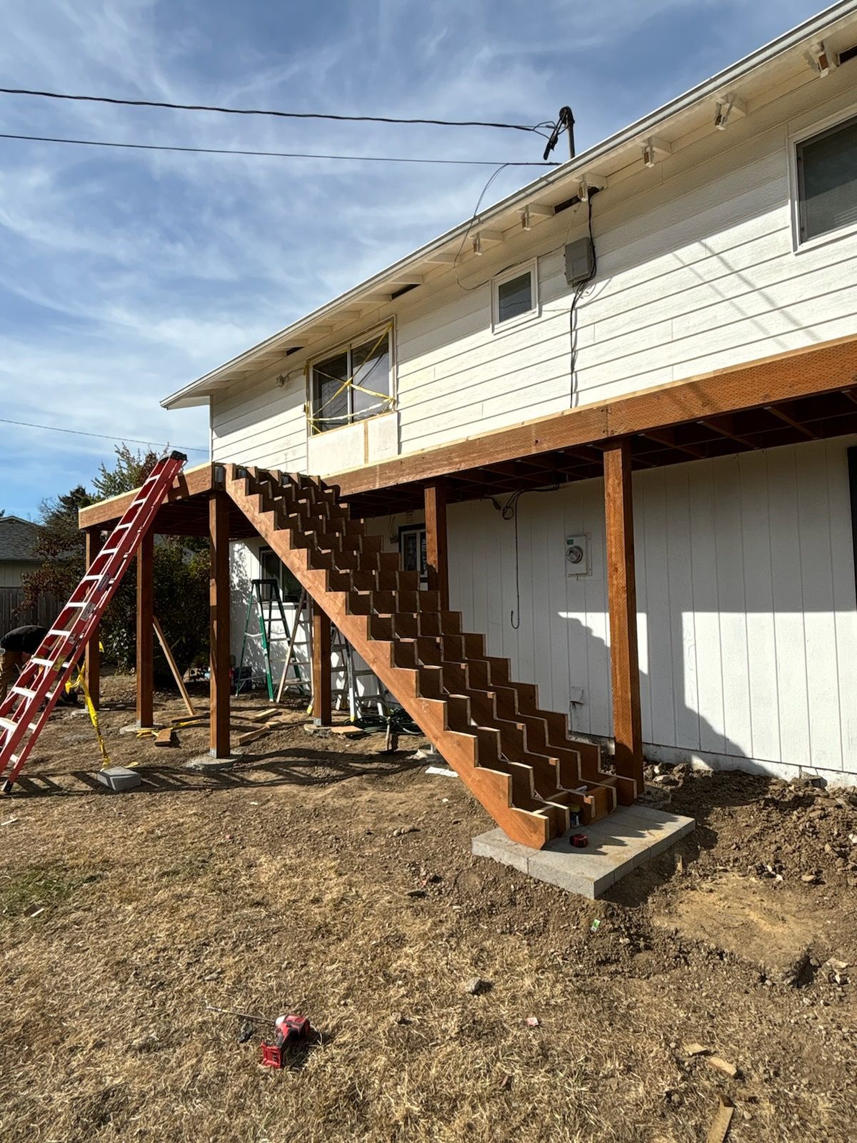 A house with a wooden deck and stairs on the side of it.
