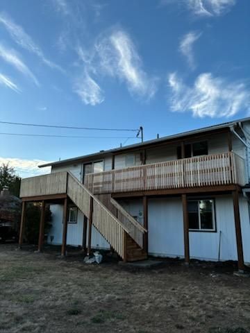A house with a wooden deck and stairs in front of it.