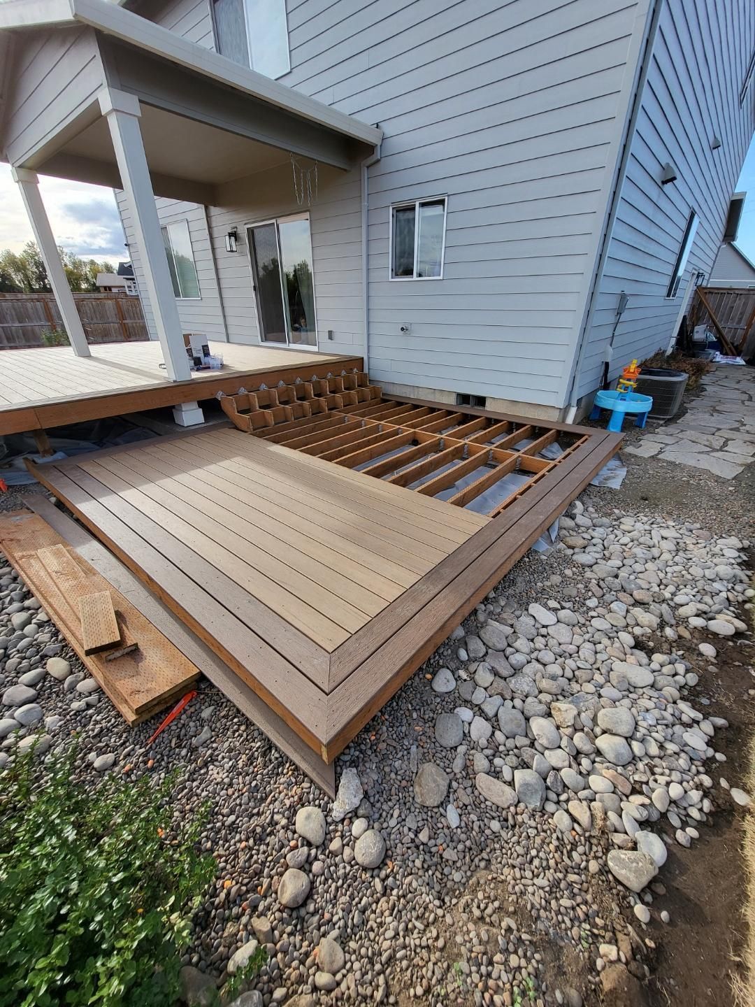 A wooden deck is being built in the backyard of a house.
