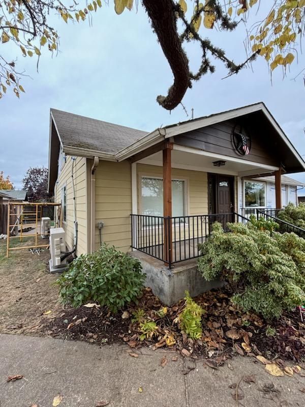 A small house with a porch and a fence in front of it.