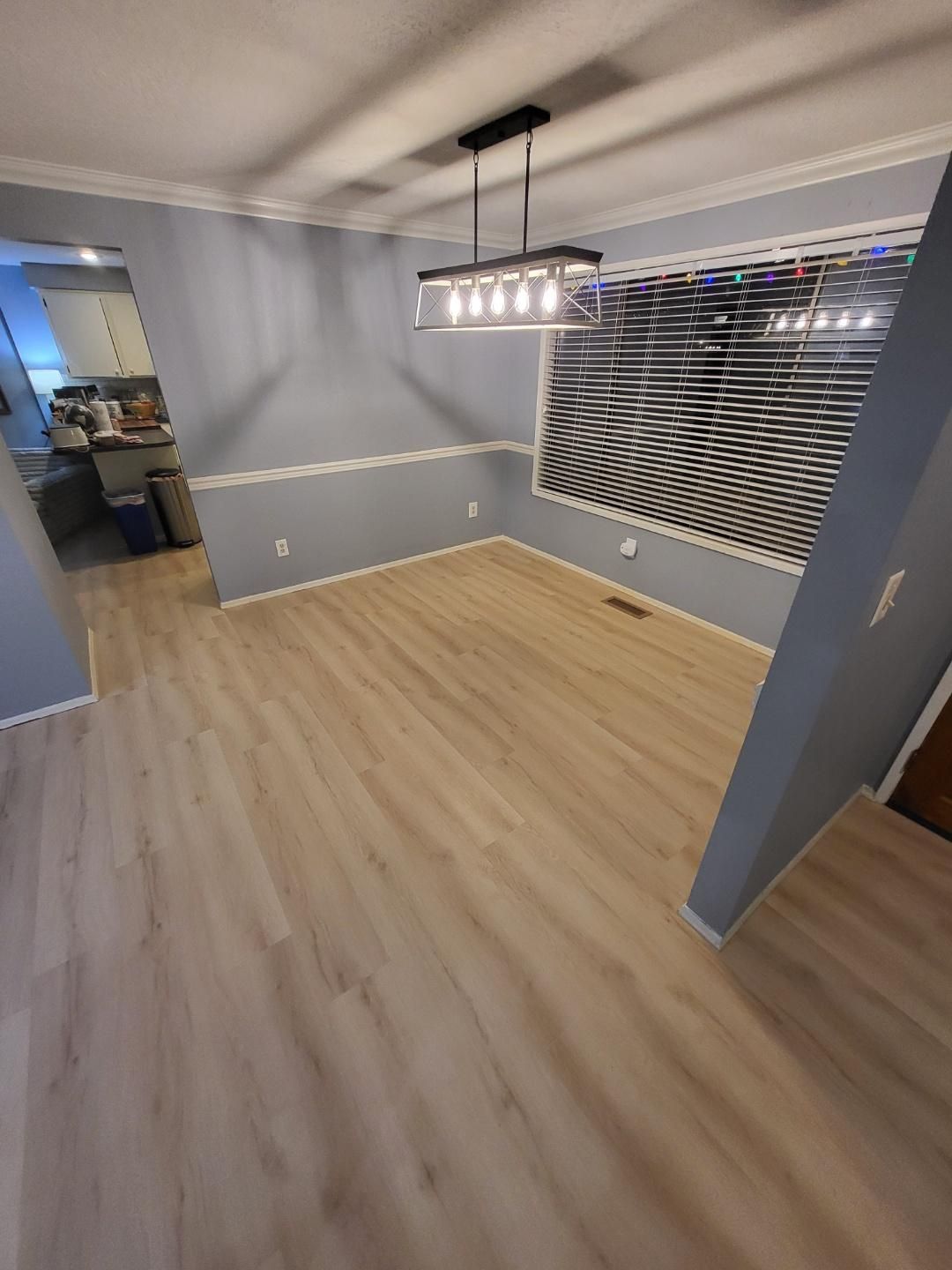 An empty dining room with hardwood floors and a window.