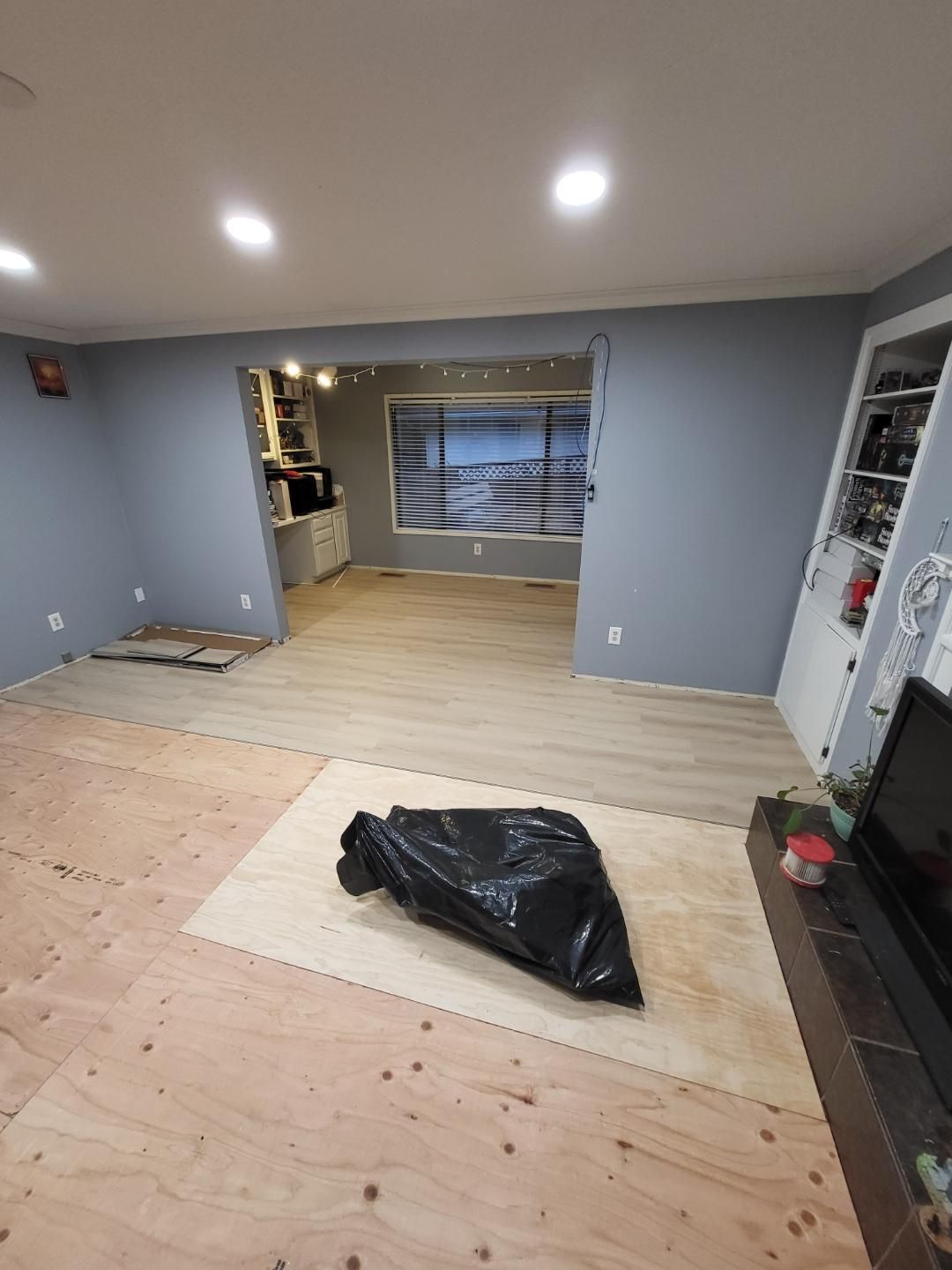A living room with hardwood floors and a black bag on the floor.