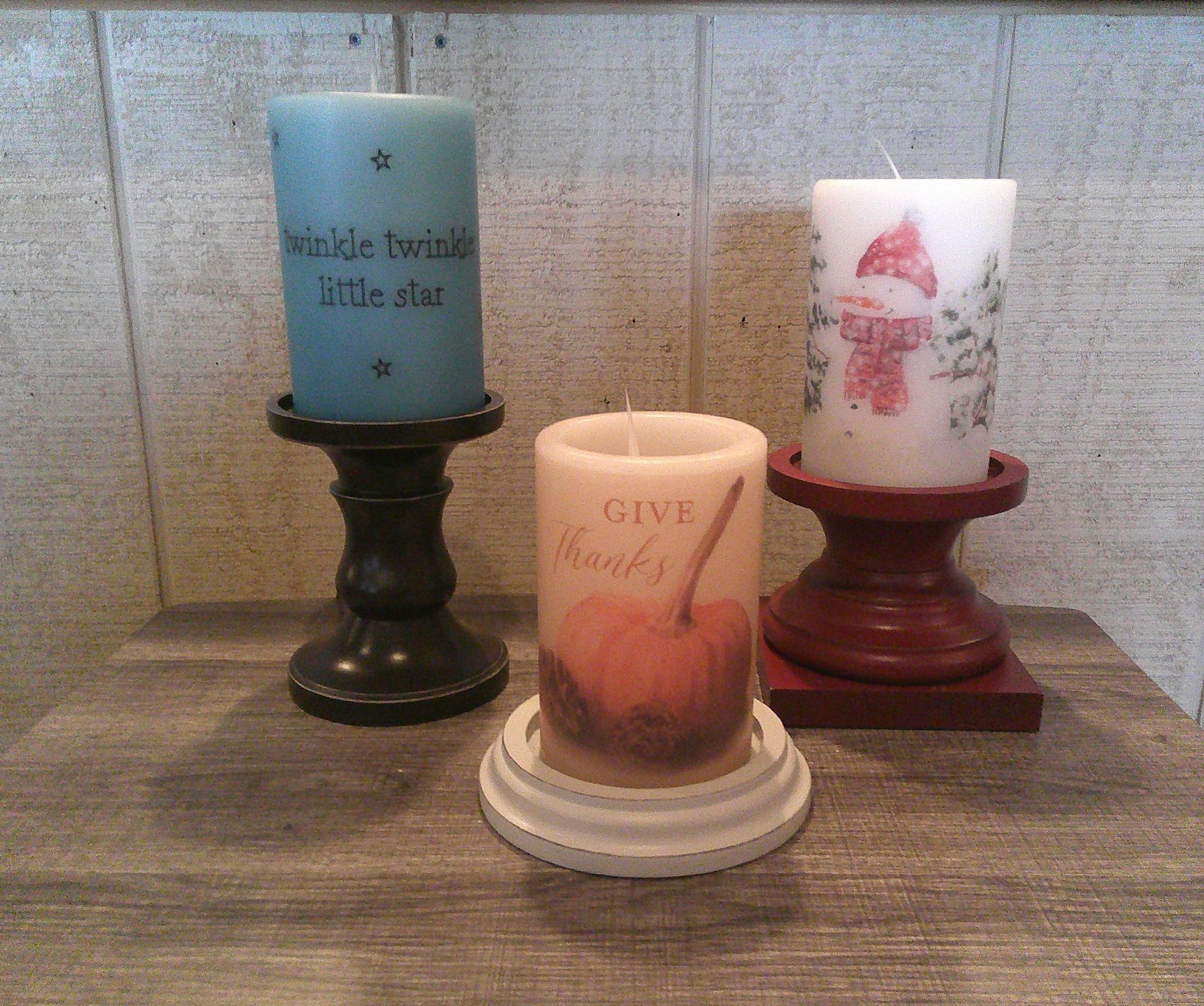Three candles on a table with one that says give thanks
