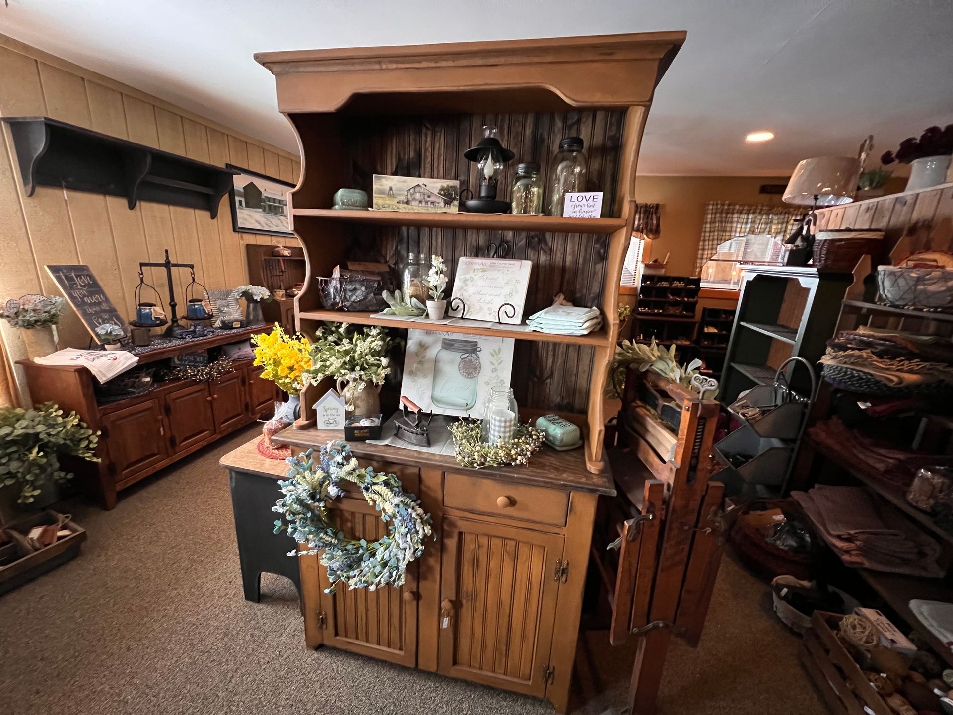 A wooden hutch with a wreath on top of it in a room.