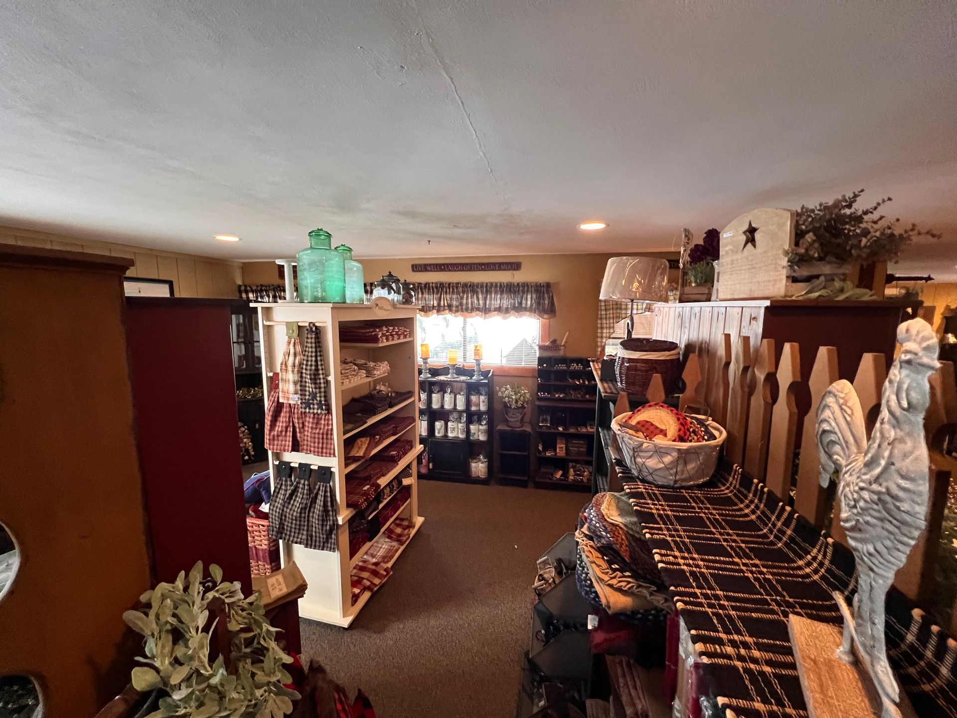 A store with a lot of shelves and a table with a bowl of fruit on it.