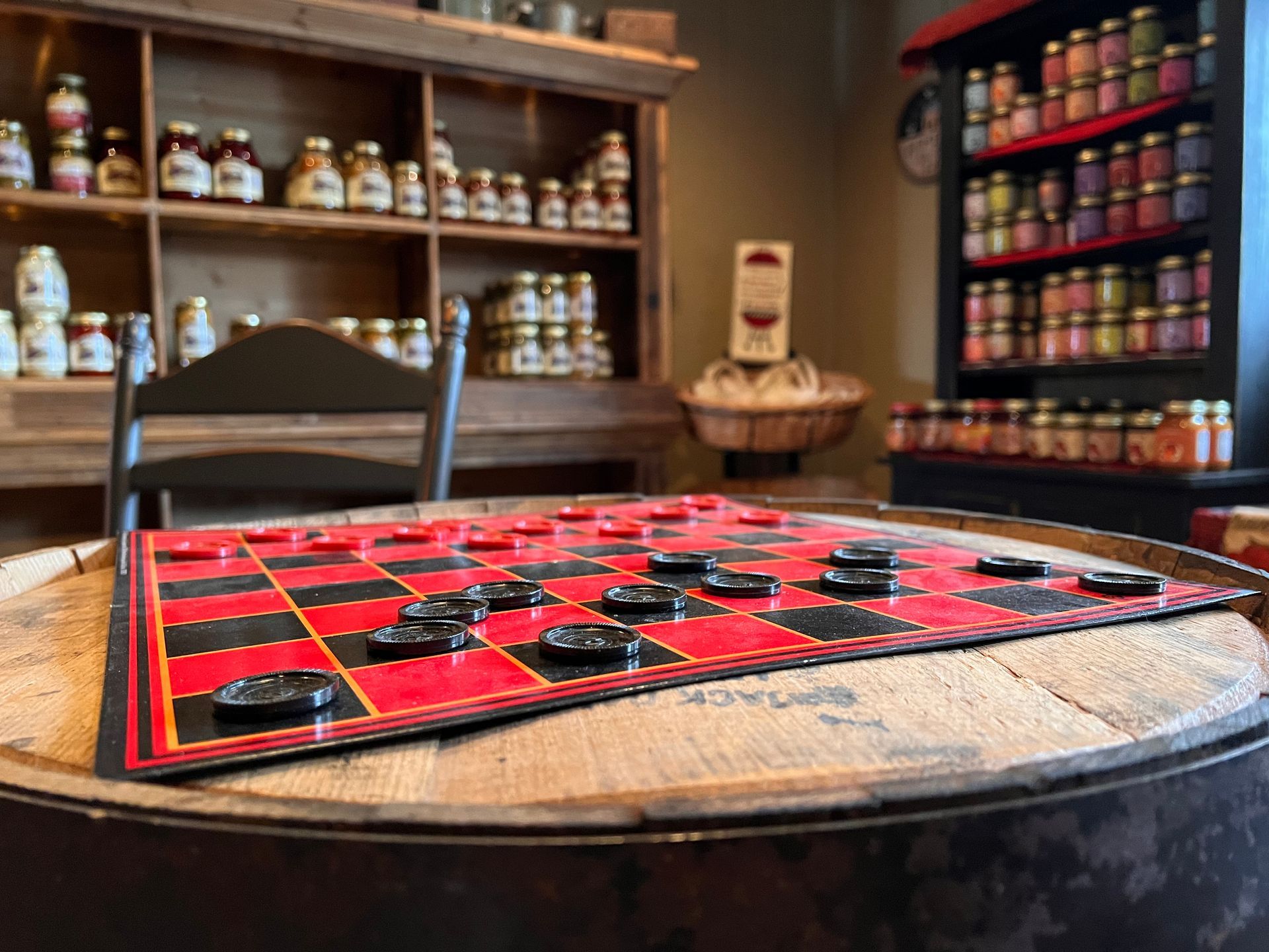 A checkers board is sitting on top of a wooden barrel.