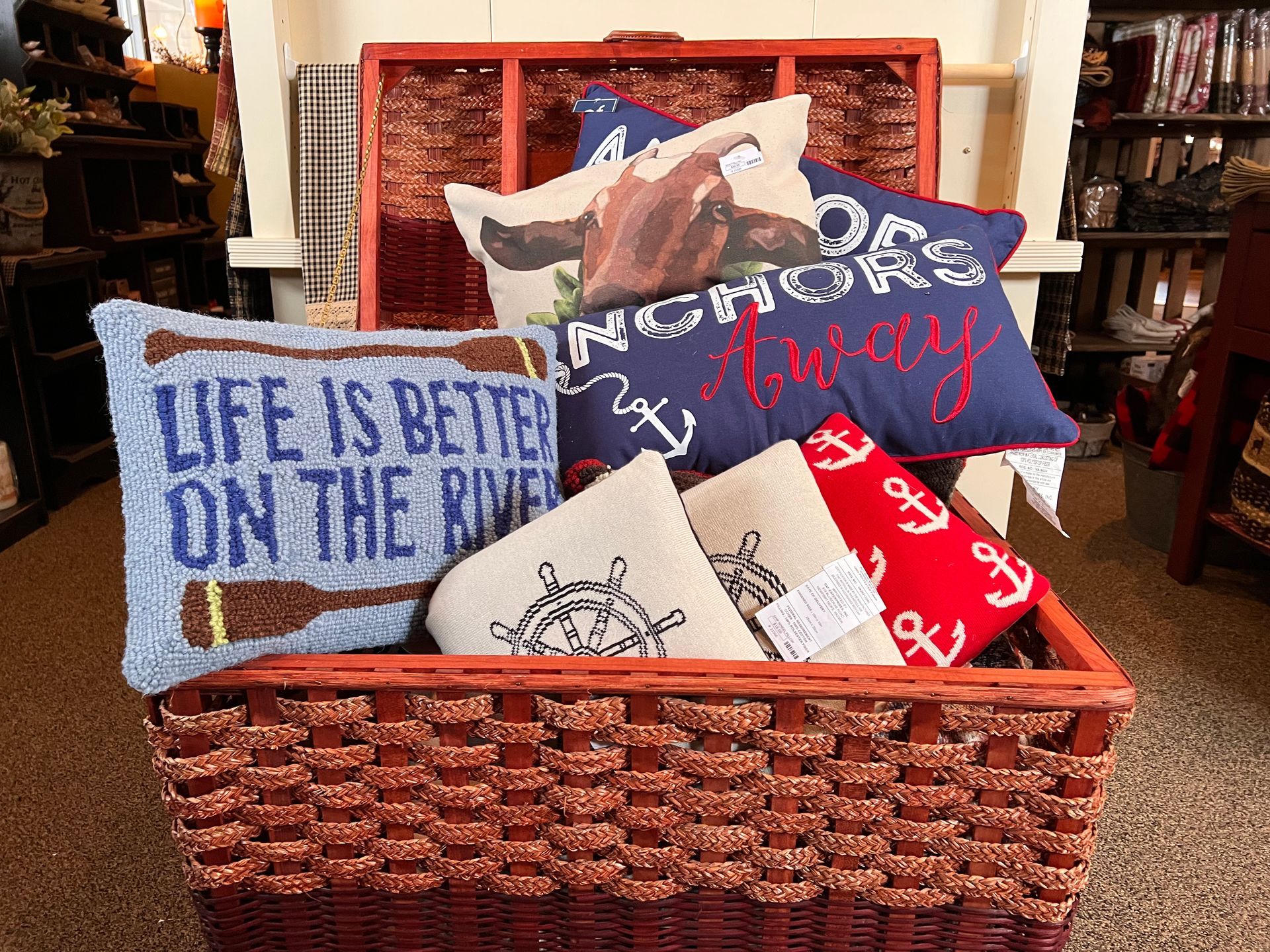 A basket filled with pillows including one that says life is better on the river