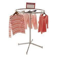 A round clothes rack with clothes hanging on it.