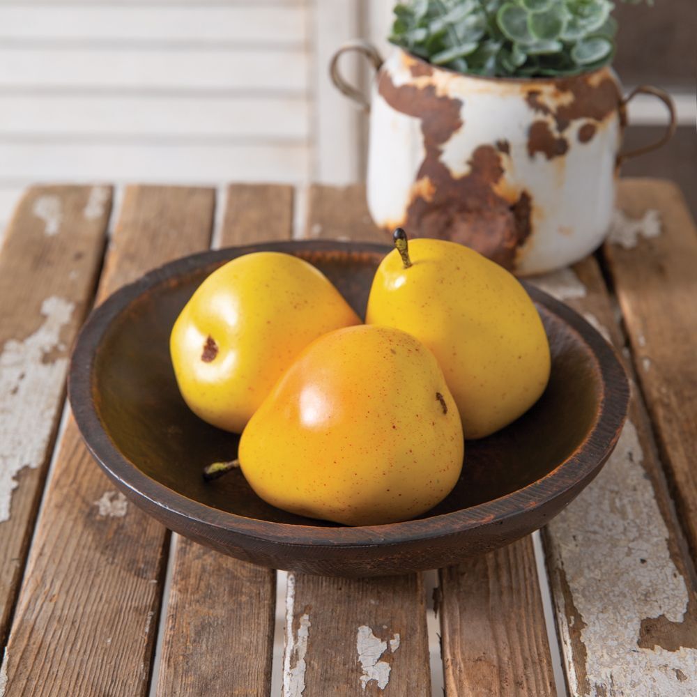 Three yellow pears in a bowl on a wooden table