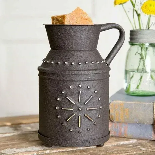 A black milk can shaped wax warmer is sitting on a wooden table.