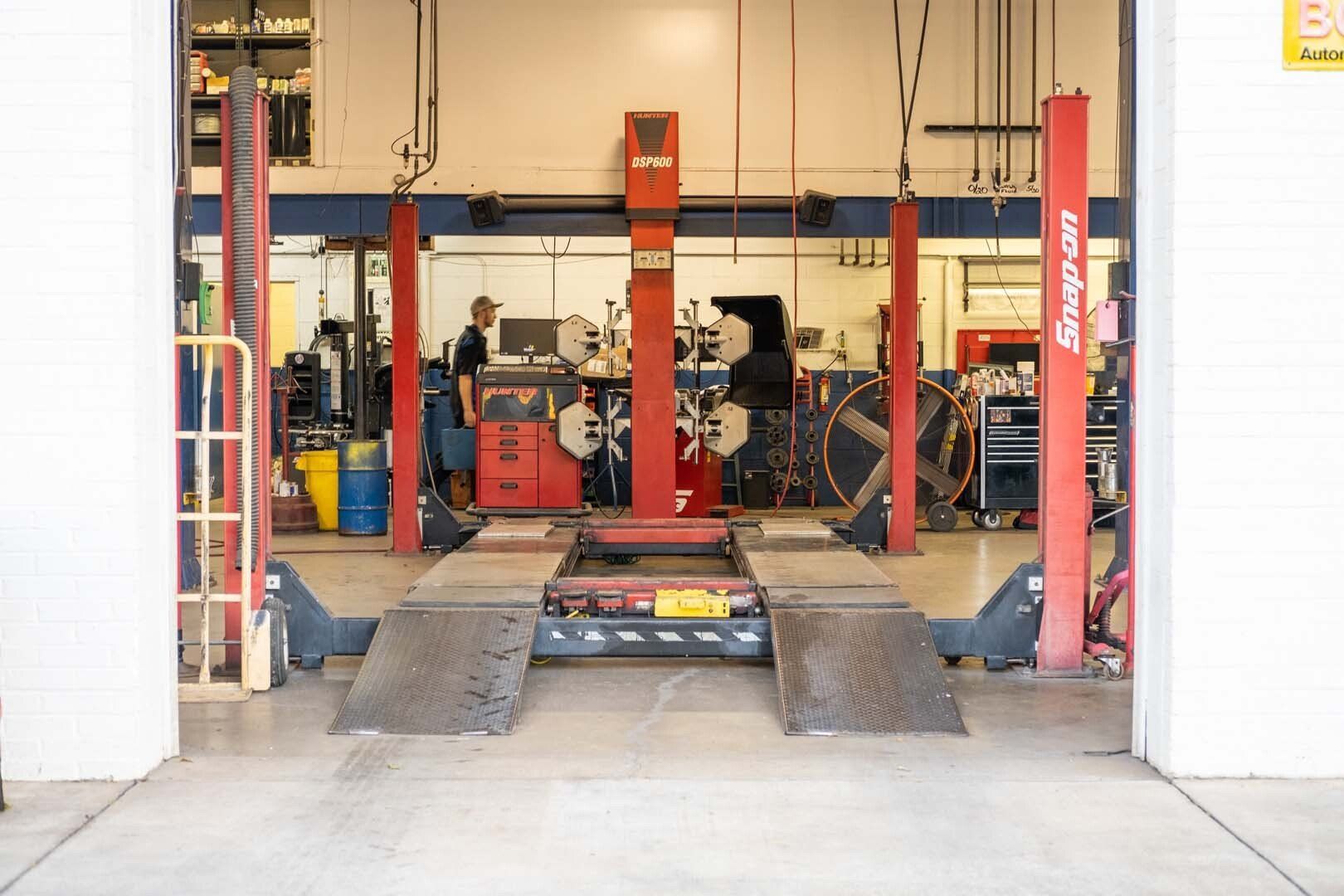Automotive repair shop interior with car lift and two mechanics working.