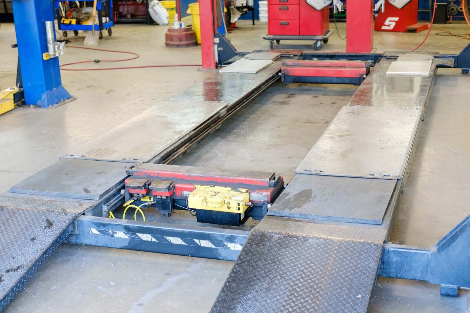 A car lift in an auto shop. Ramps lead to a raised platform with mechanical components.