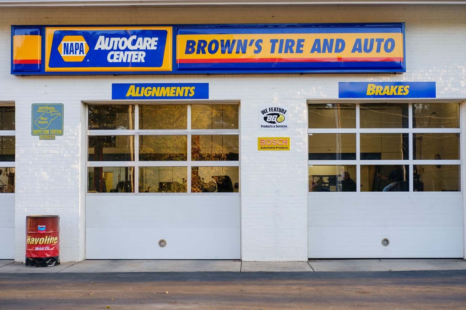 Brown's Tire and Auto shop with blue and yellow signage, two garage doors, and alignment/brakes signs above them.