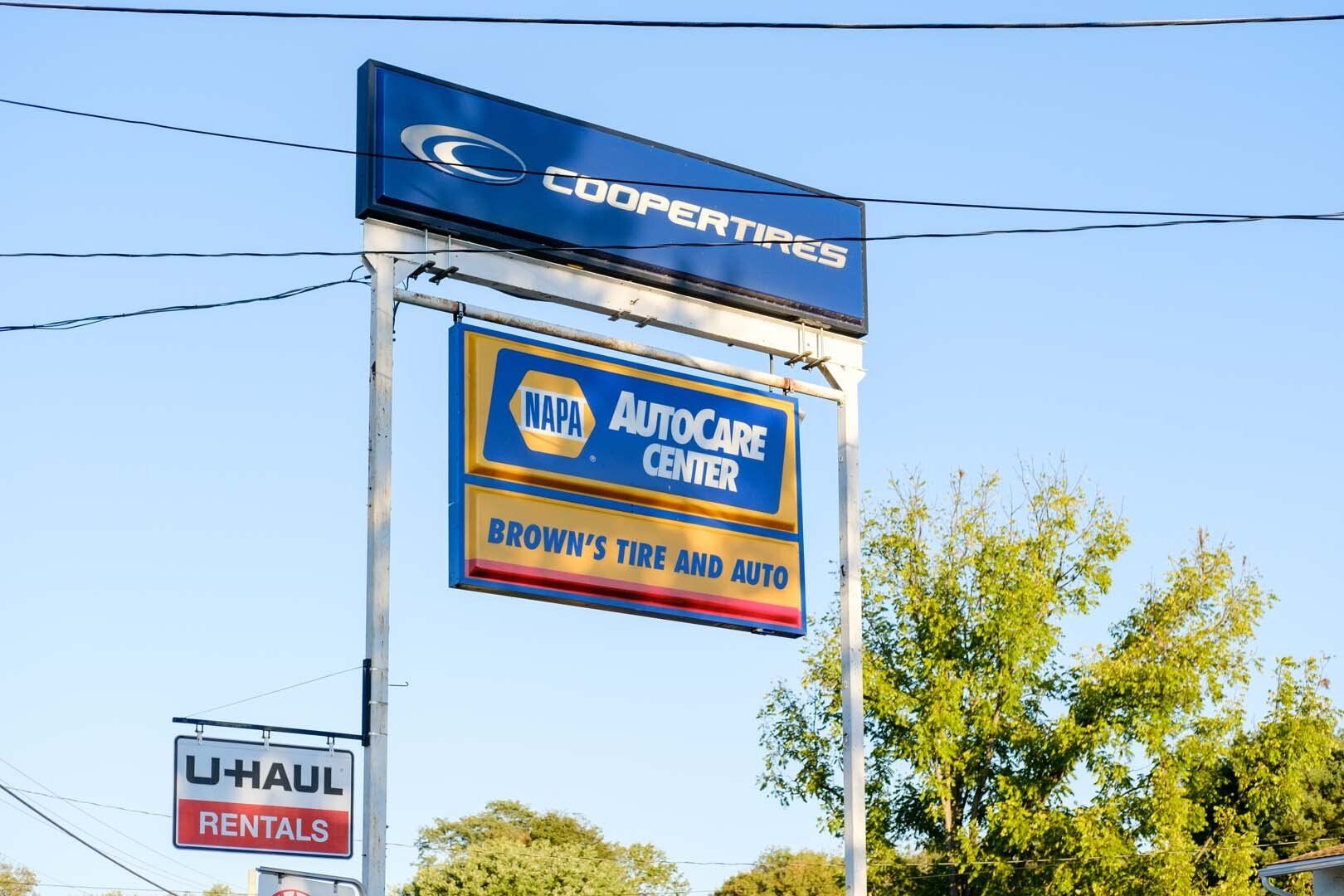 Sign for Cooper Tires, NAPA AutoCare Center, and U-Haul Rentals against a blue sky.