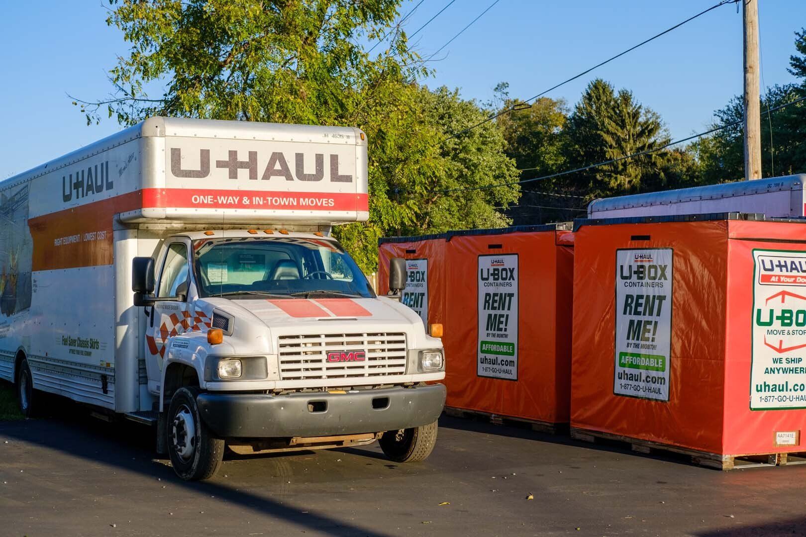 U-Haul truck and two orange U-Box storage containers parked outside, ready for moving.