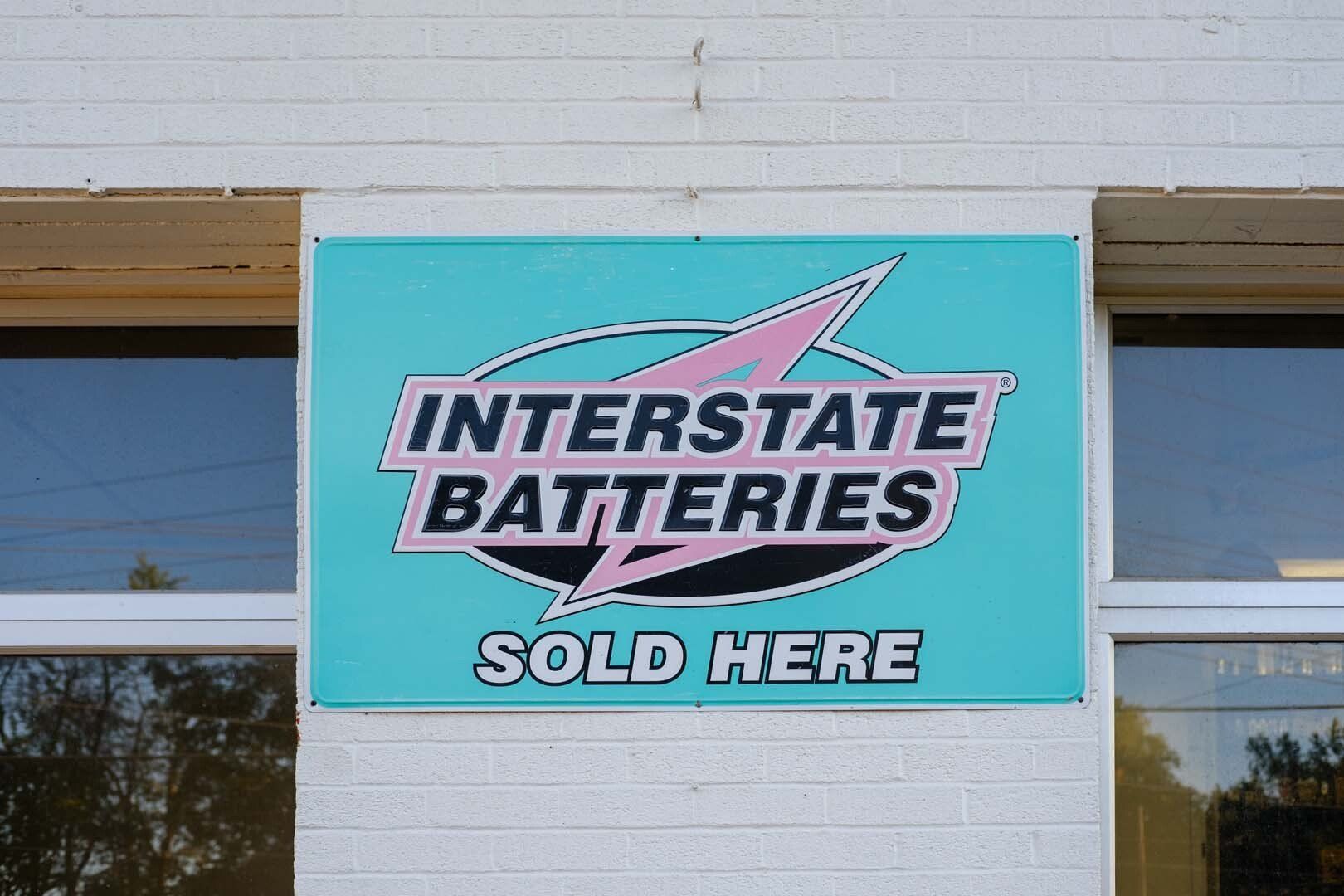 Sign for Interstate Batteries, turquoise background, pink and black logo, 