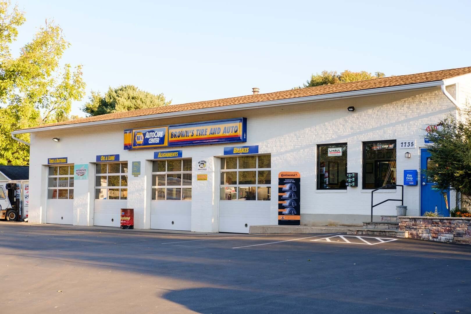 White auto repair shop with garage doors, blue accents, and signage. Paved lot in front.