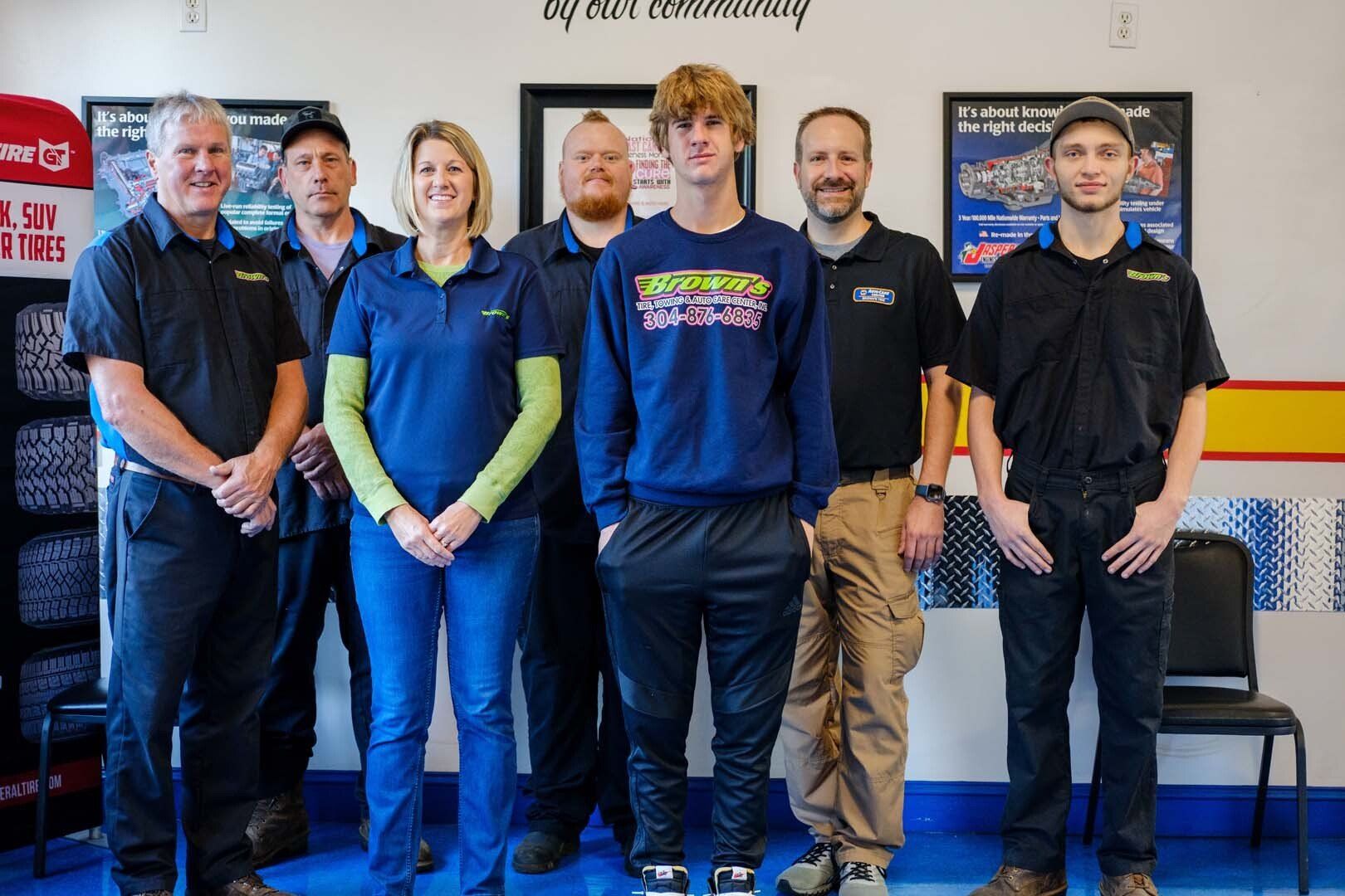 Group of people standing in a shop. People are wearing work uniforms and smiling.