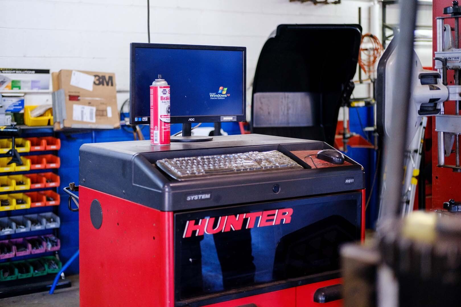 Hunter wheel balancer machine in a shop. Red and black with monitor and keyboard.